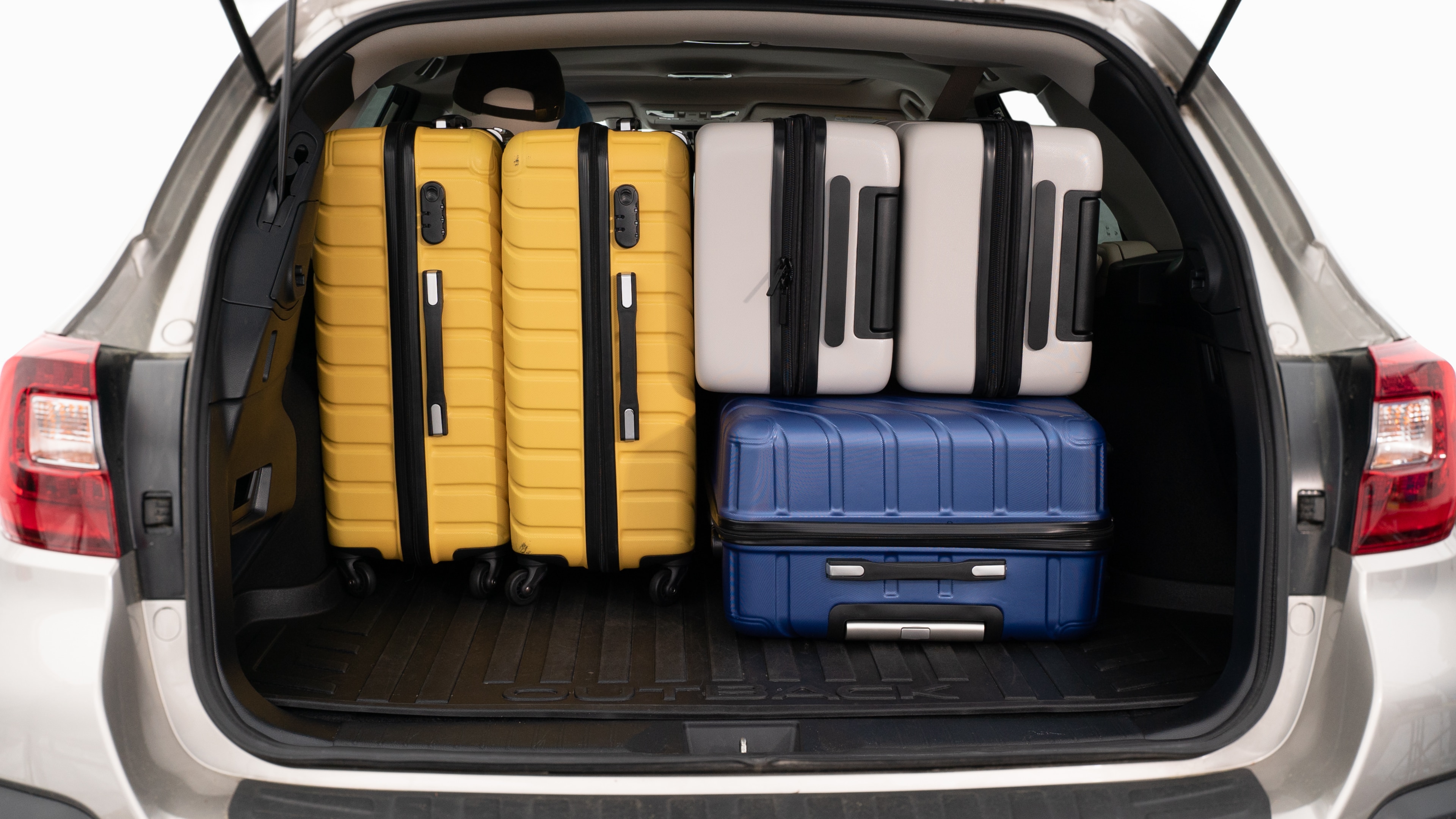 The trunk lid is open, showing a full view of the trunk space. Three large and two small suitcases are placed inside.
