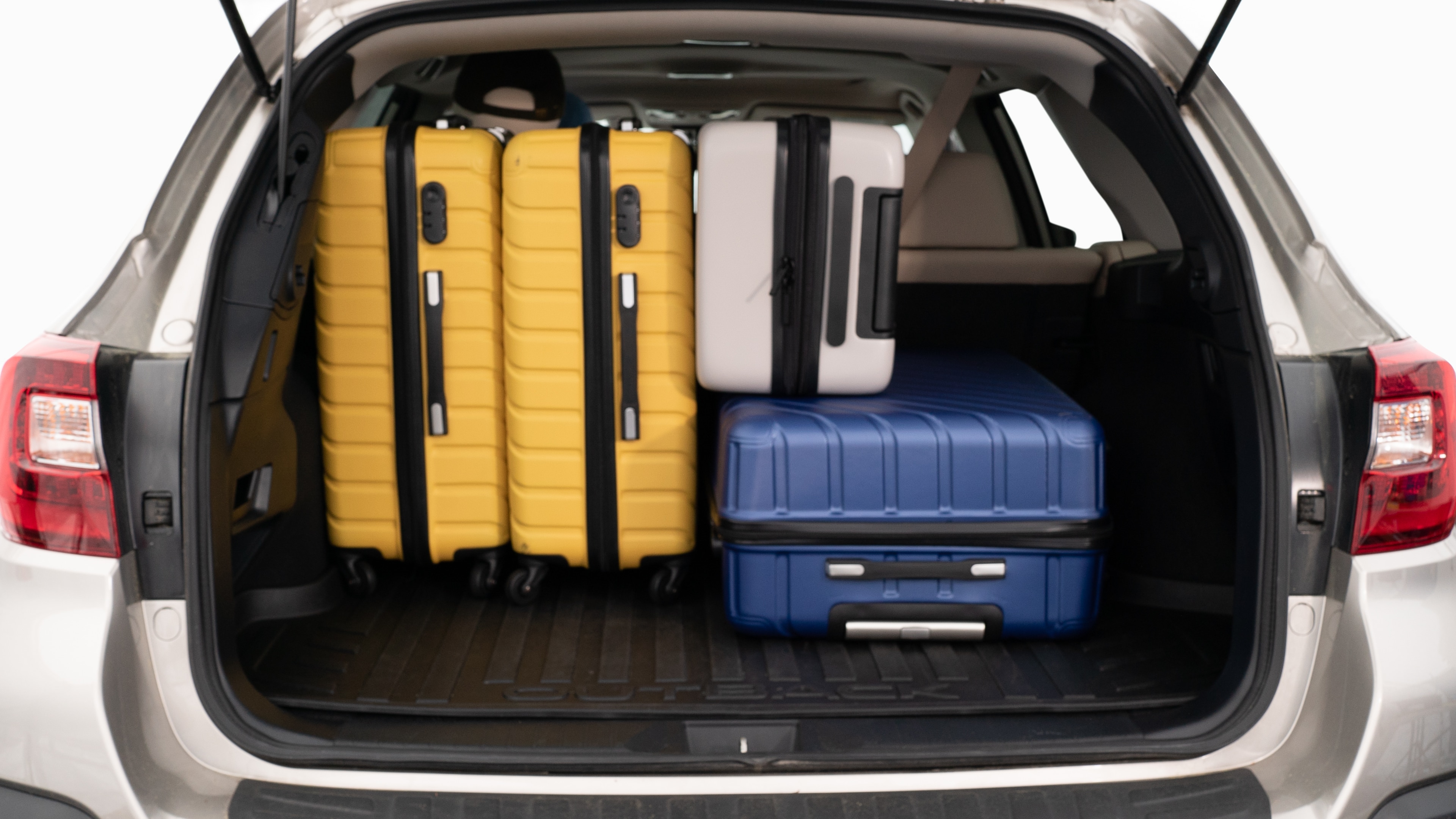 The trunk lid is open, showing a full view of the trunk space. Three large and two small suitcases are placed inside.