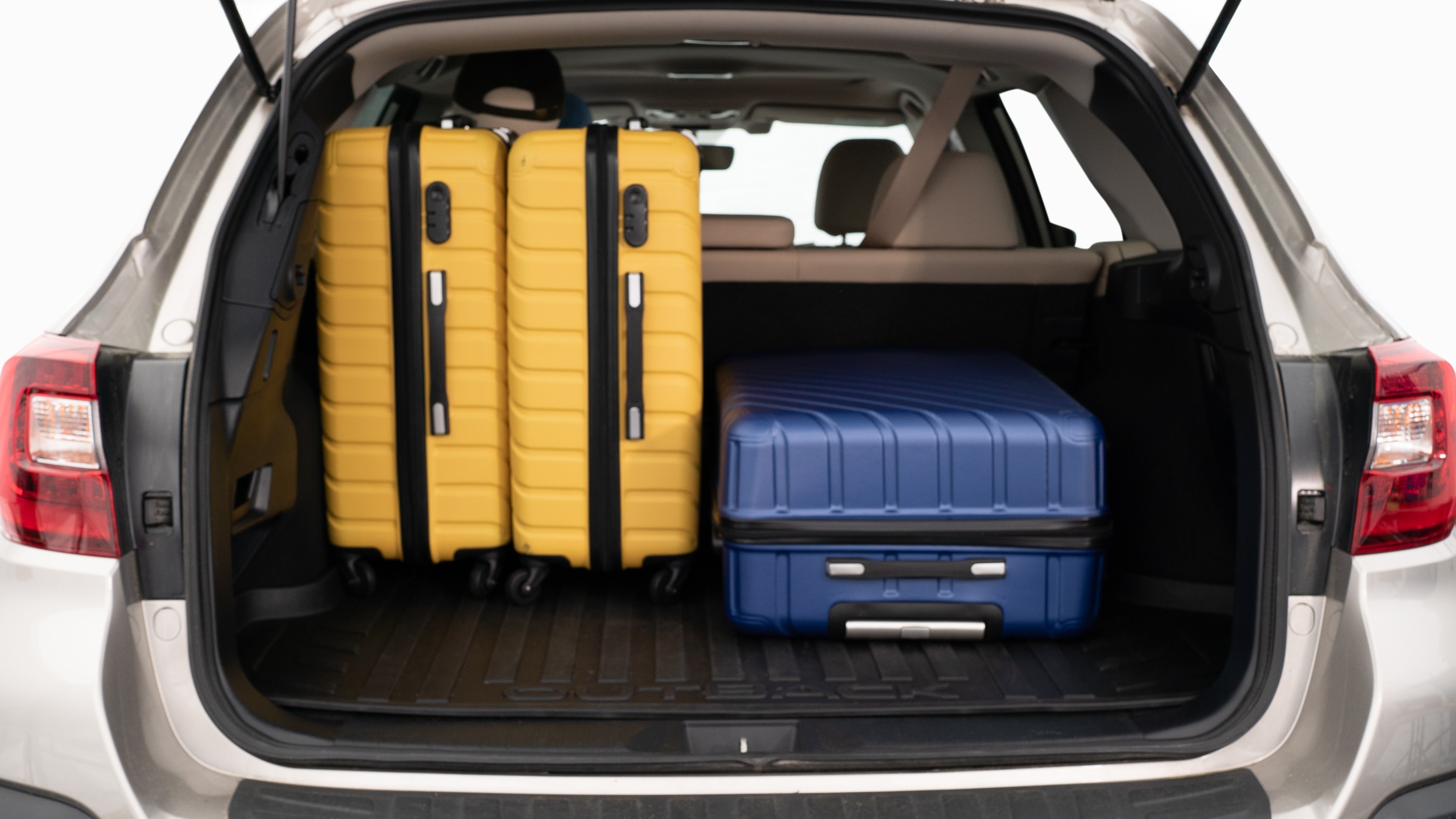 The trunk lid is open, showing a full view of the trunk space. Three large and two small suitcases are placed inside.
