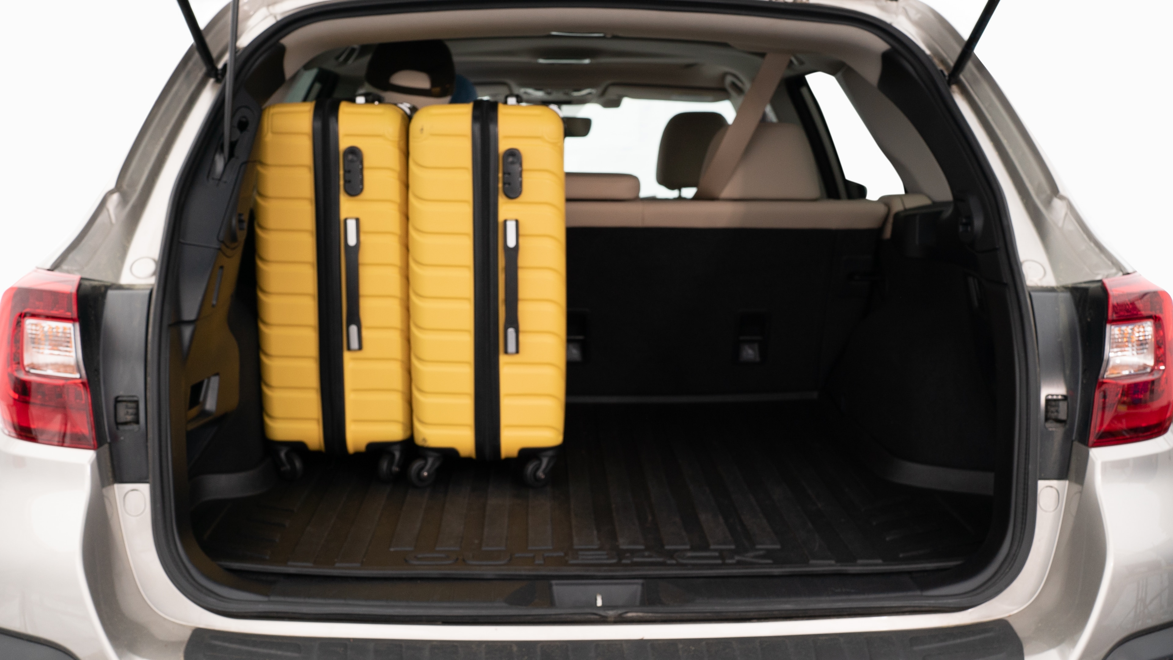 The trunk lid is open, showing a full view of the trunk space. Three large and two small suitcases are placed inside.