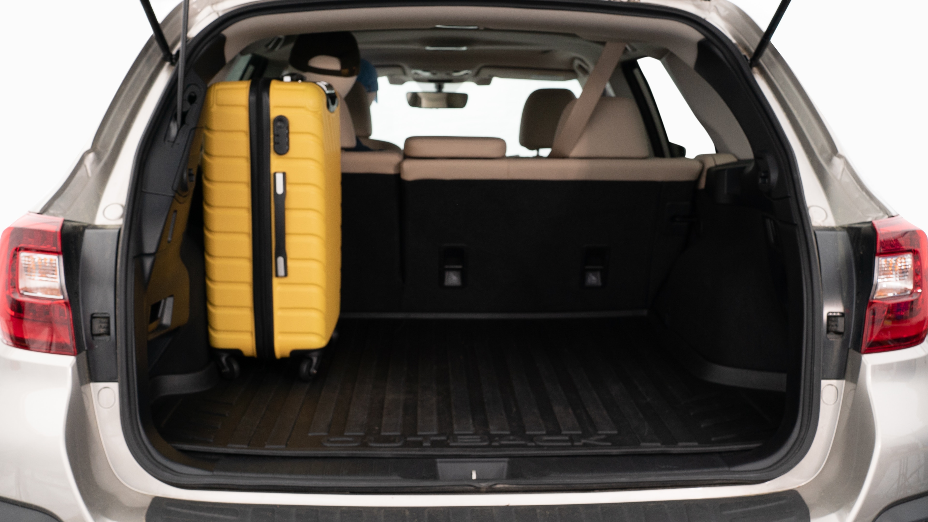 The trunk lid is open, showing a full view of the trunk space. Three large and two small suitcases are placed inside.