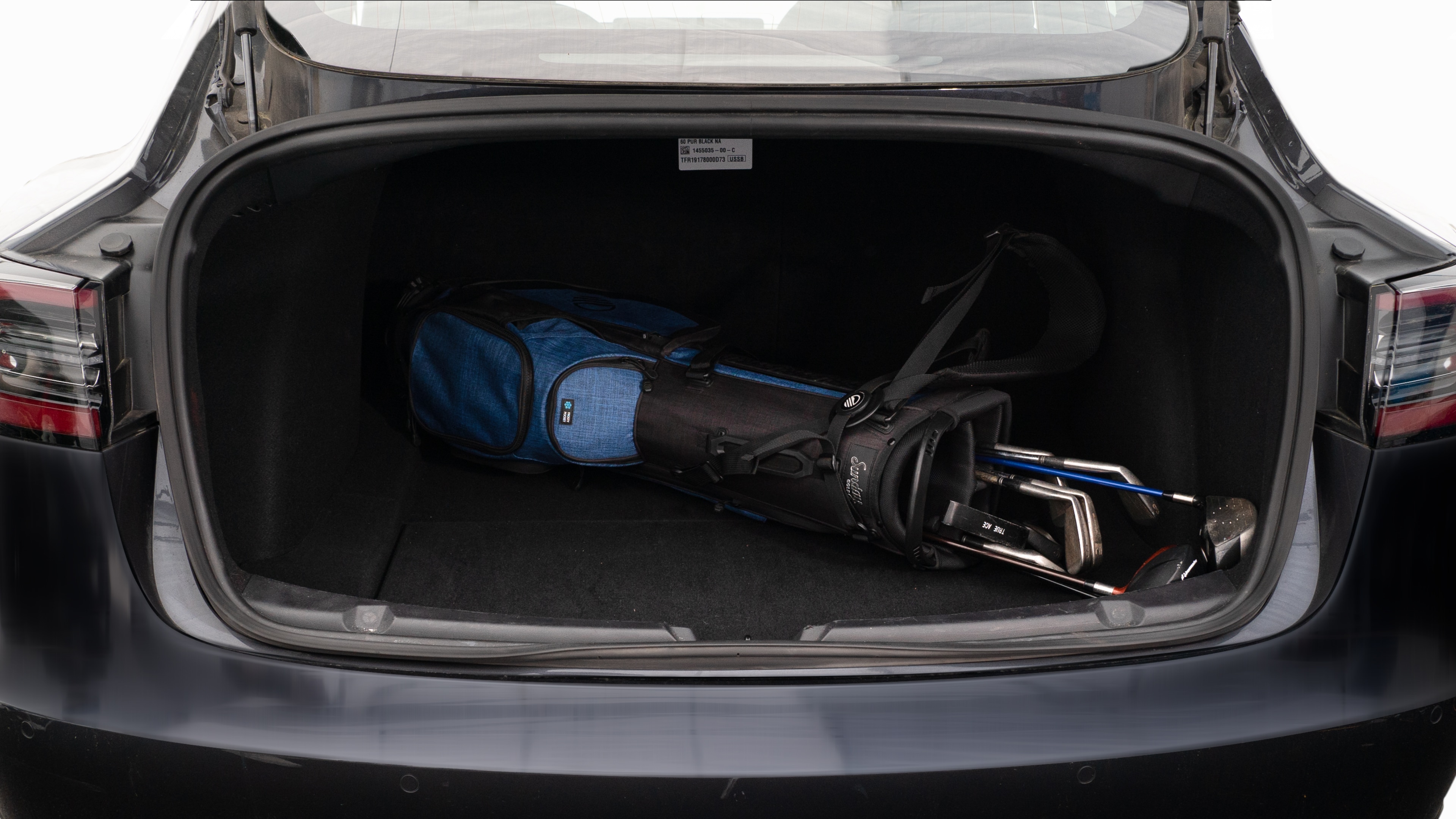 The trunk lid is open showing full view of the trunk. A baby stroller, two camping chairs in the carrying bag, and a set of golf clubs are placed inside.