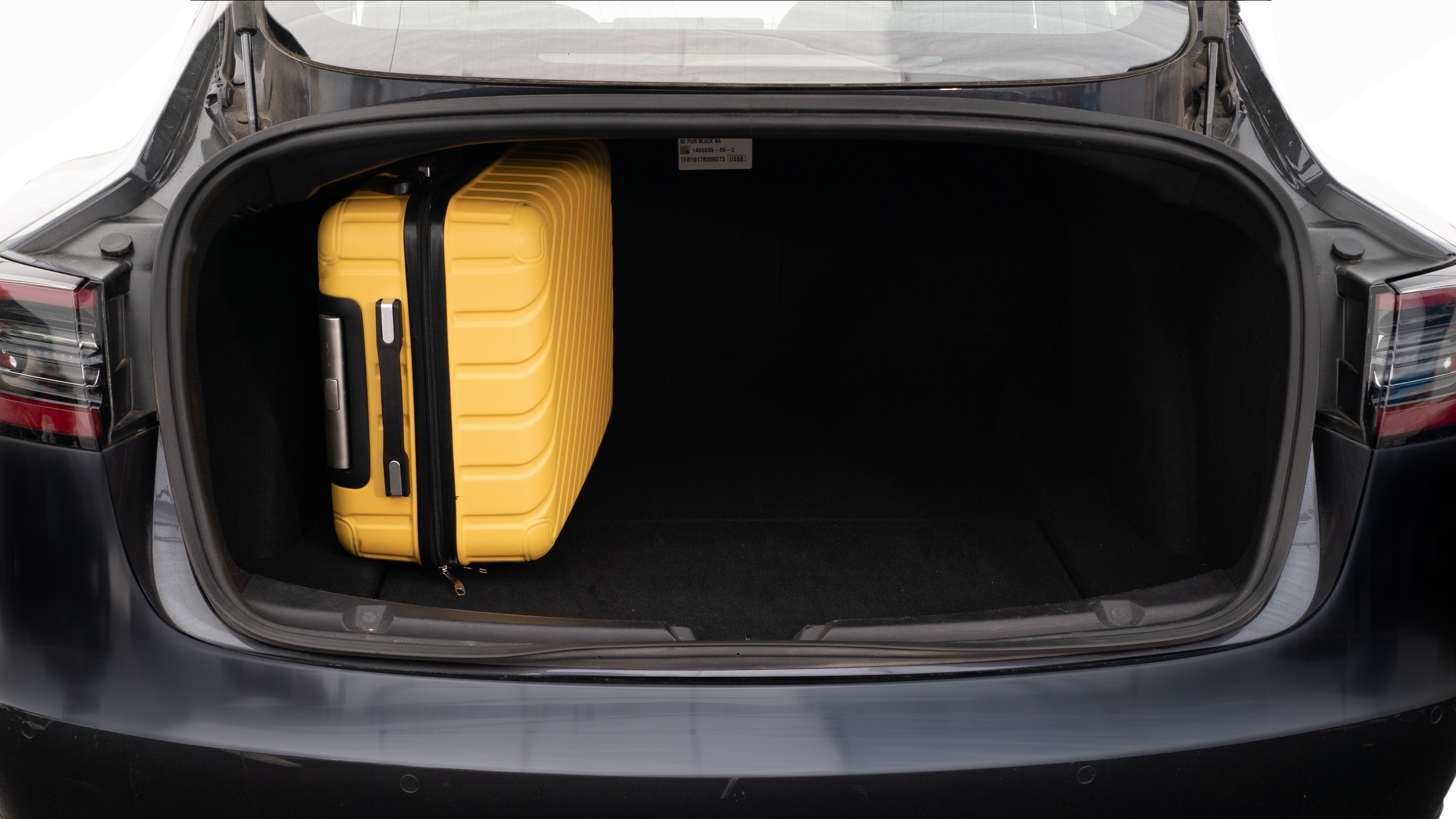 The trunk lid is open, showing a full view of the trunk space. Two large and two small suitcases are placed inside.