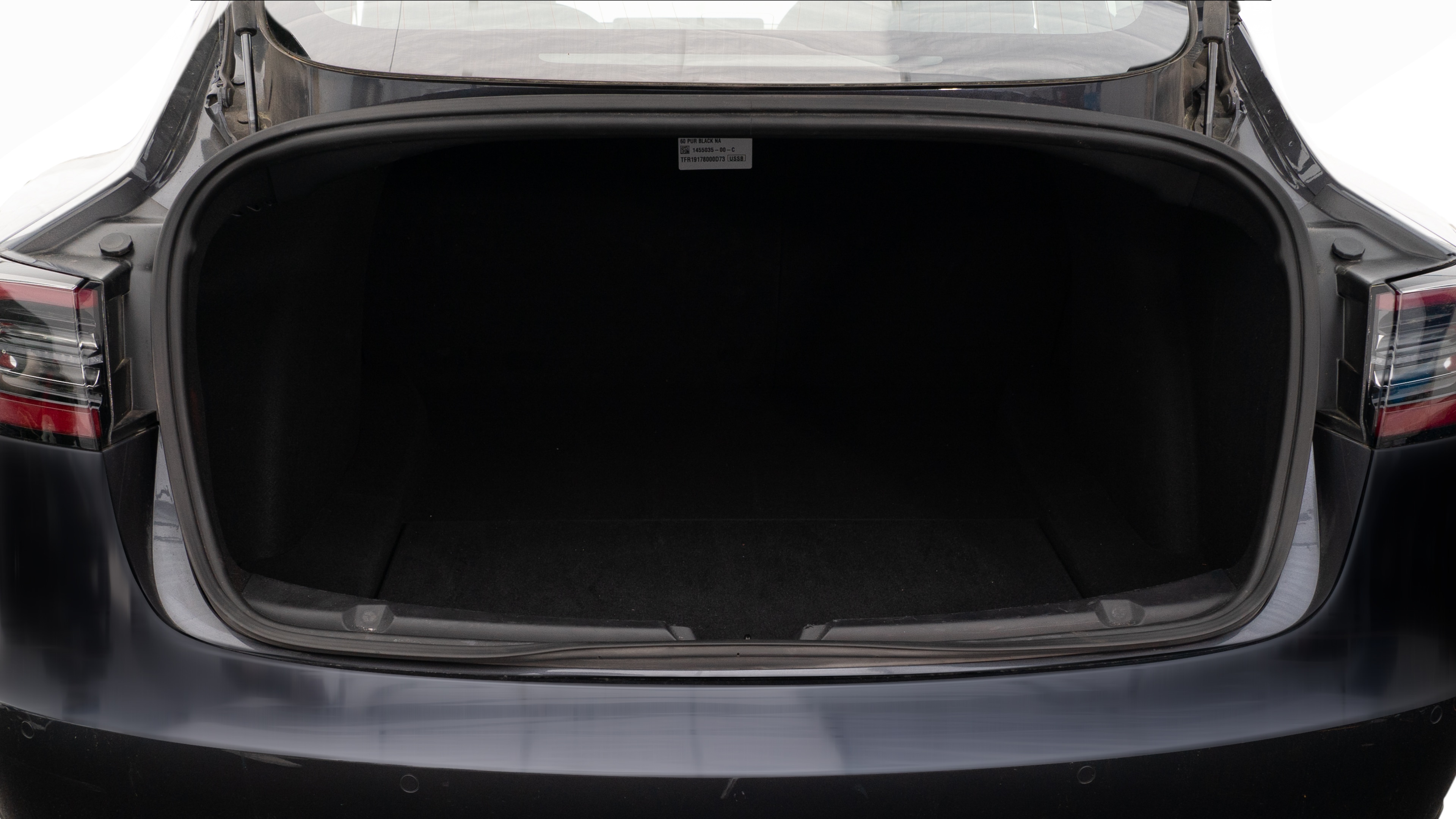 The trunk lid is open, showing a full view of the trunk space. Two large and two small suitcases are placed inside.