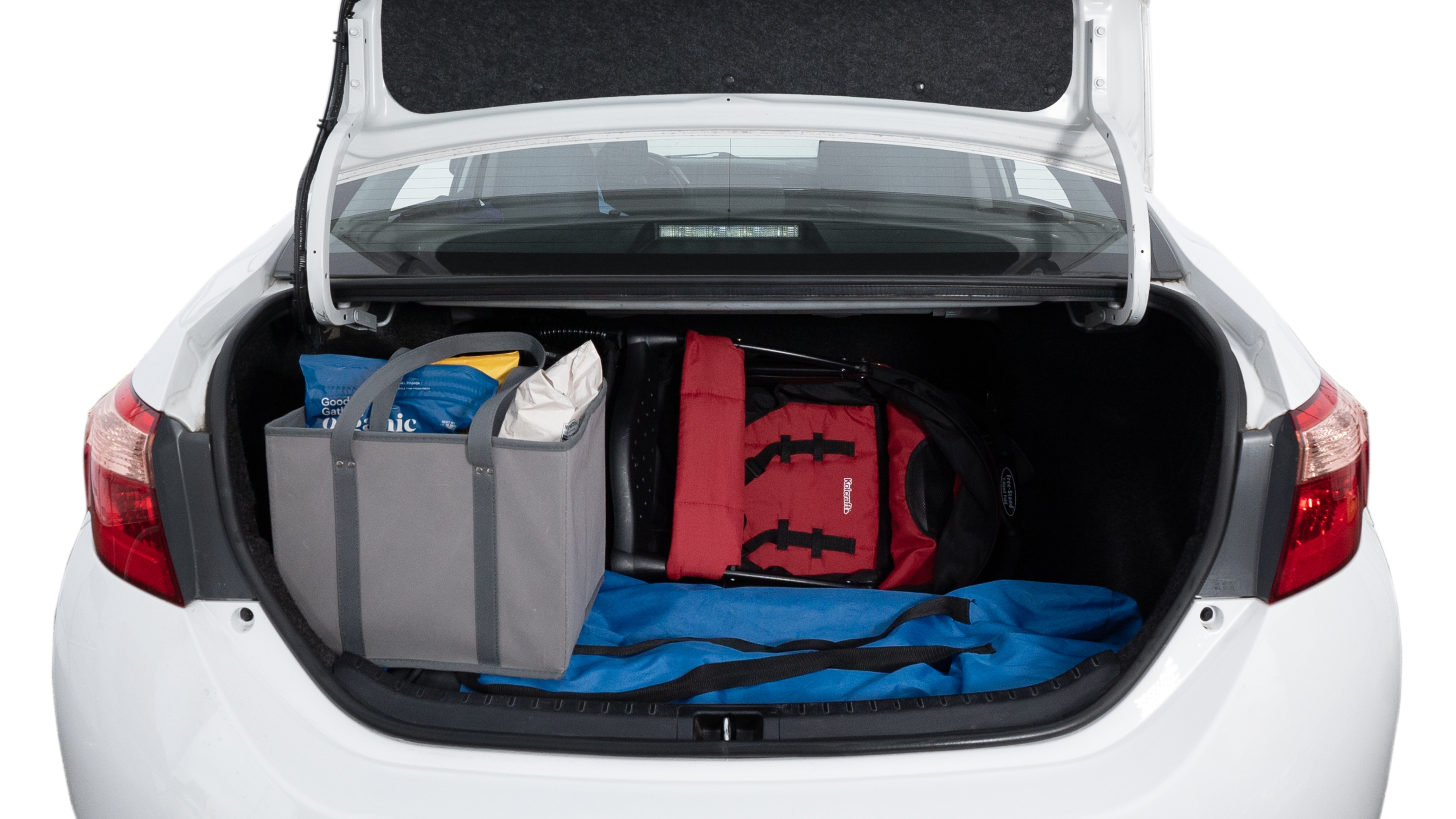 The trunk lid is open showing full view of the trunk. A baby stroller, three grocery carriers, two camping chairs in the carrying bag, and a set of golf clubs are placed inside.