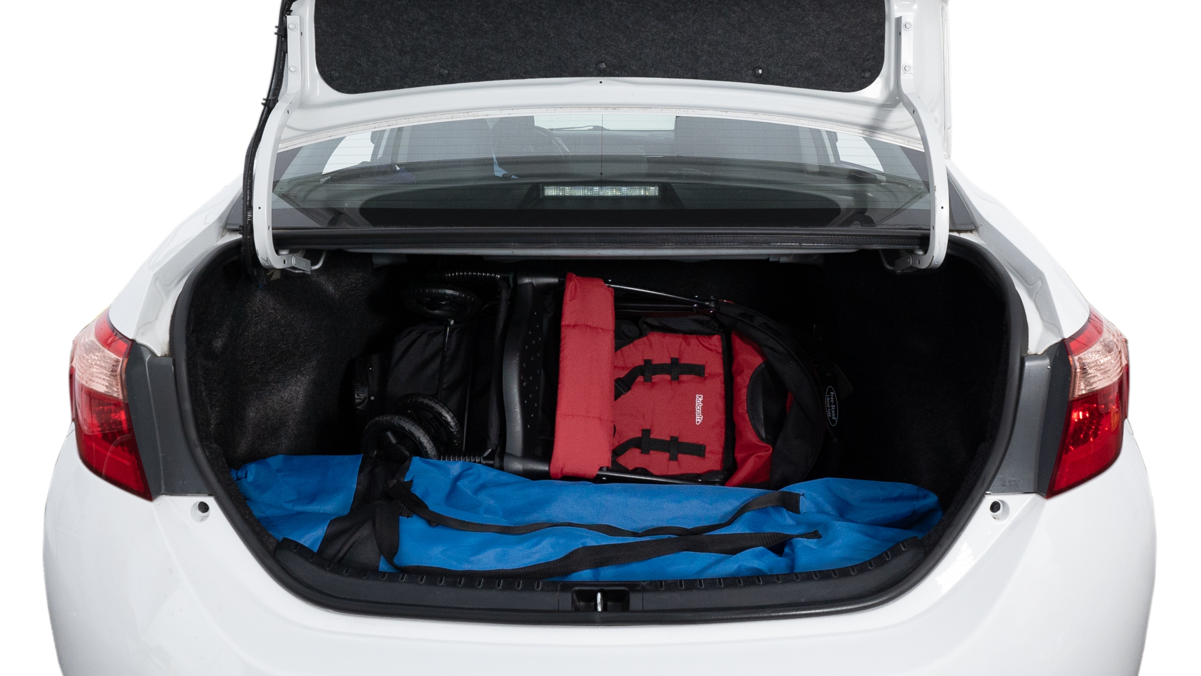 The trunk lid is open showing full view of the trunk. A baby stroller, three grocery carriers, two camping chairs in the carrying bag, and a set of golf clubs are placed inside.