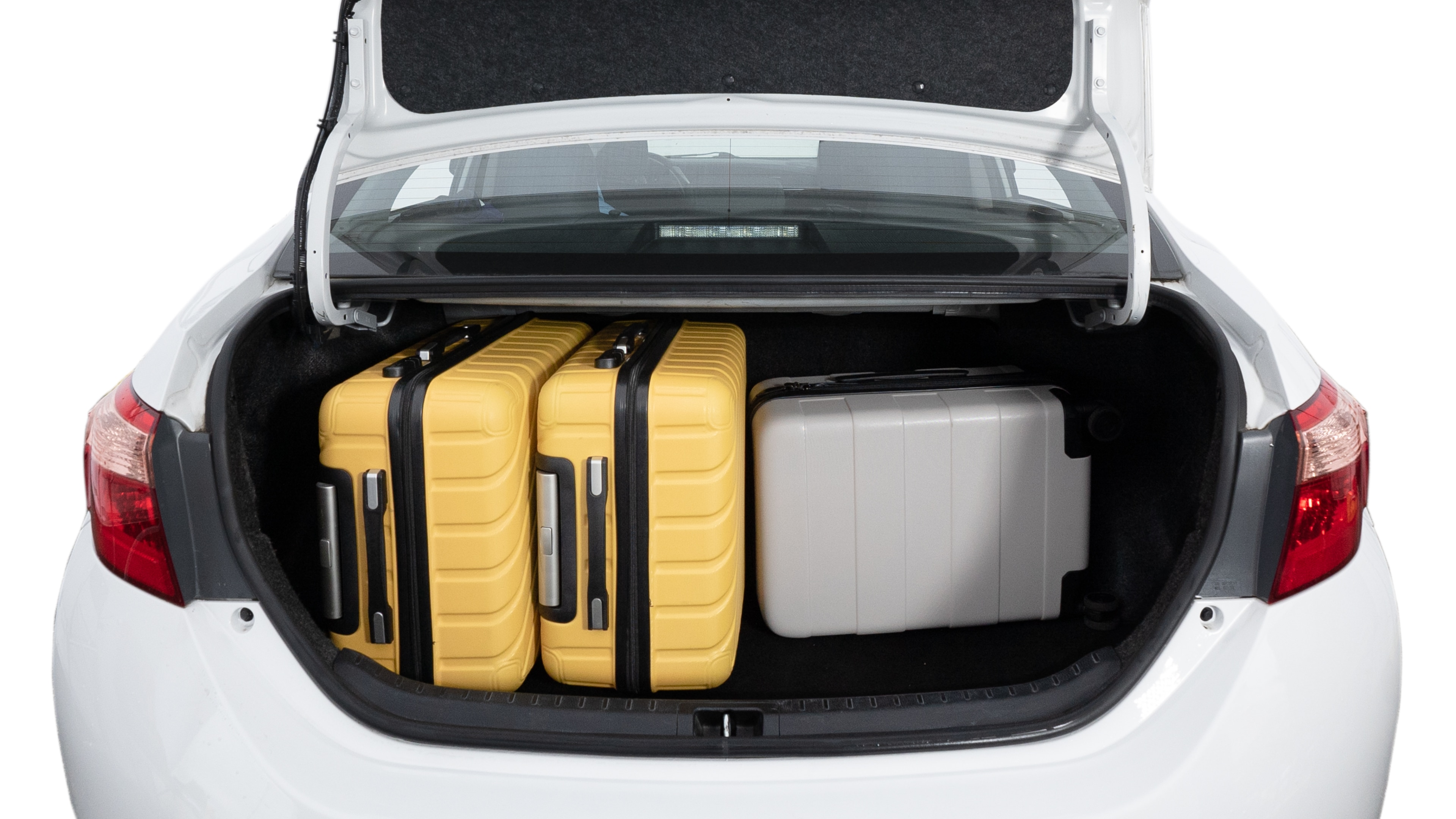 The trunk lid is open, showing a full view of the trunk space. Two medium and two small suitcases are placed inside