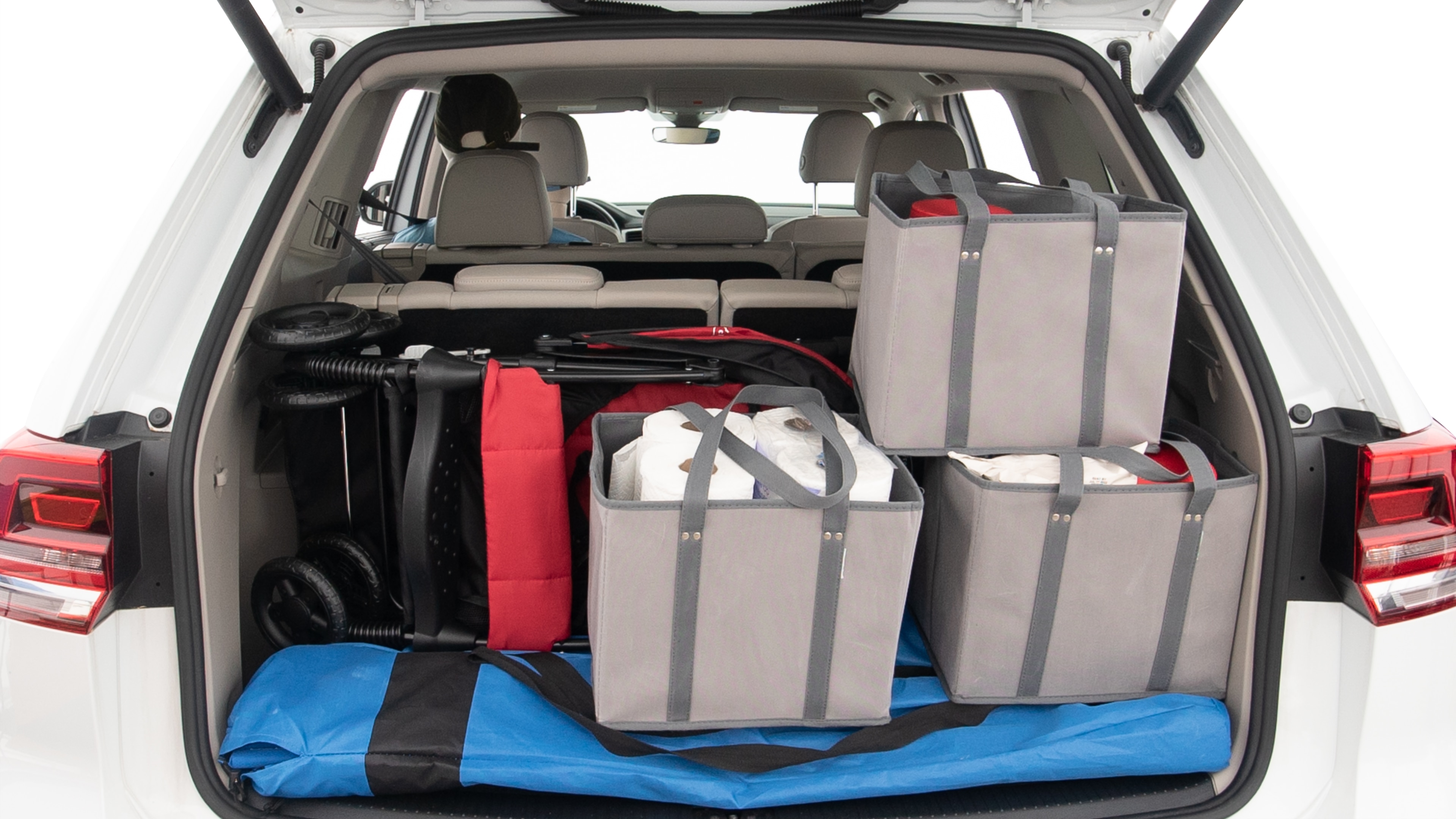 The trunk lid is open showing full view of the trunk. A baby stroller, three grocery carriers, two camping chairs in the carrying bag, and a set of golf clubs are placed inside.
