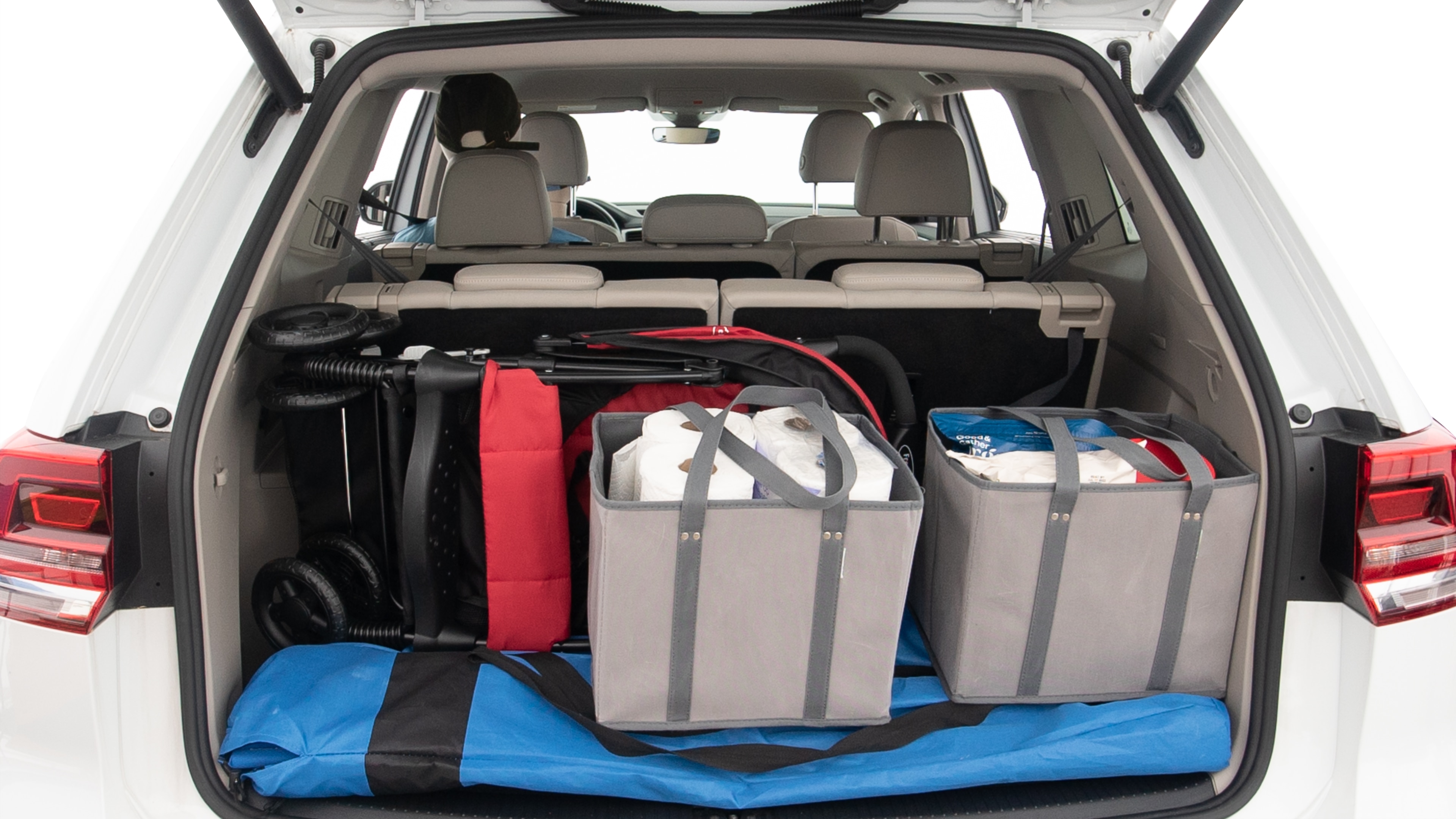 The trunk lid is open showing full view of the trunk. A baby stroller, three grocery carriers, two camping chairs in the carrying bag, and a set of golf clubs are placed inside.