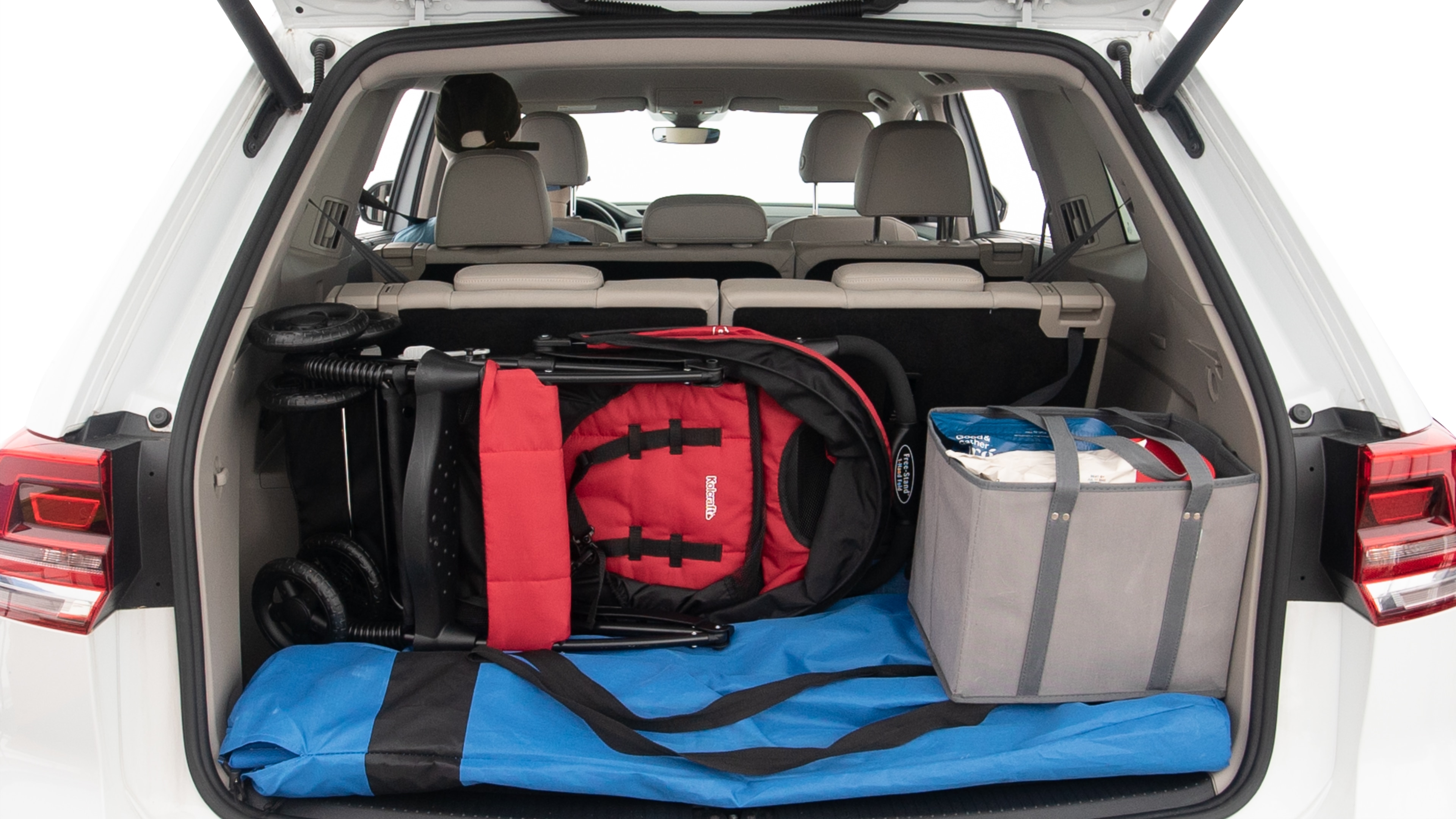 The trunk lid is open showing full view of the trunk. A baby stroller, three grocery carriers, two camping chairs in the carrying bag, and a set of golf clubs are placed inside.