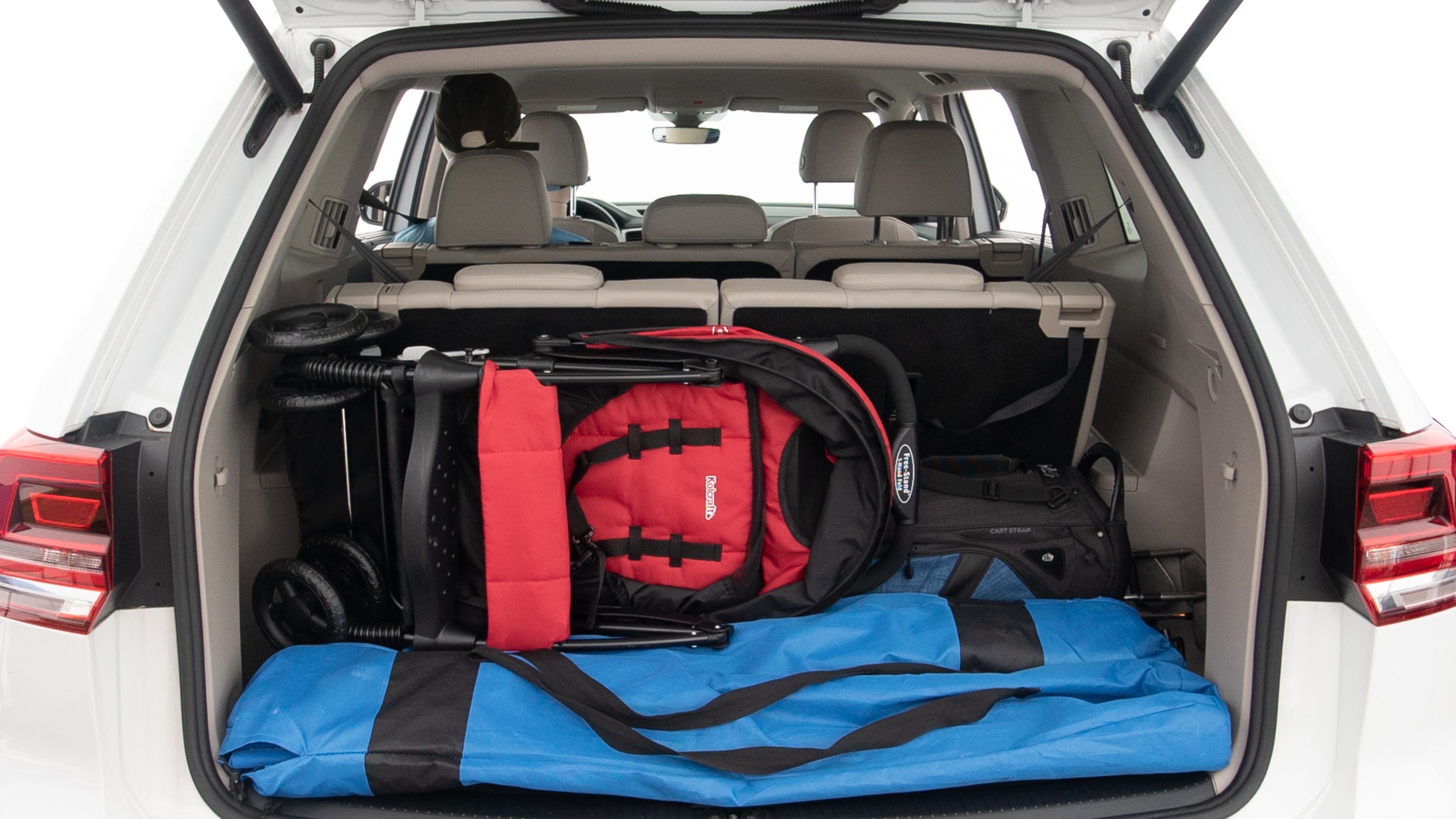 The trunk lid is open showing full view of the trunk. A baby stroller, three grocery carriers, two camping chairs in the carrying bag, and a set of golf clubs are placed inside.