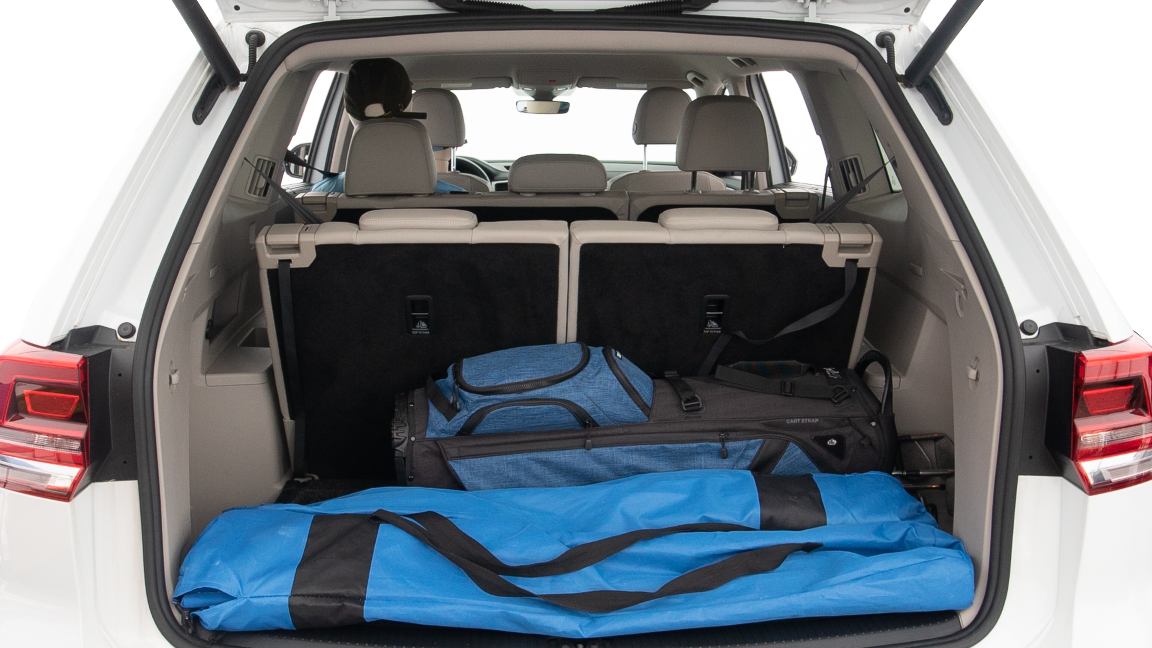 The trunk lid is open showing full view of the trunk. A baby stroller, three grocery carriers, two camping chairs in the carrying bag, and a set of golf clubs are placed inside.