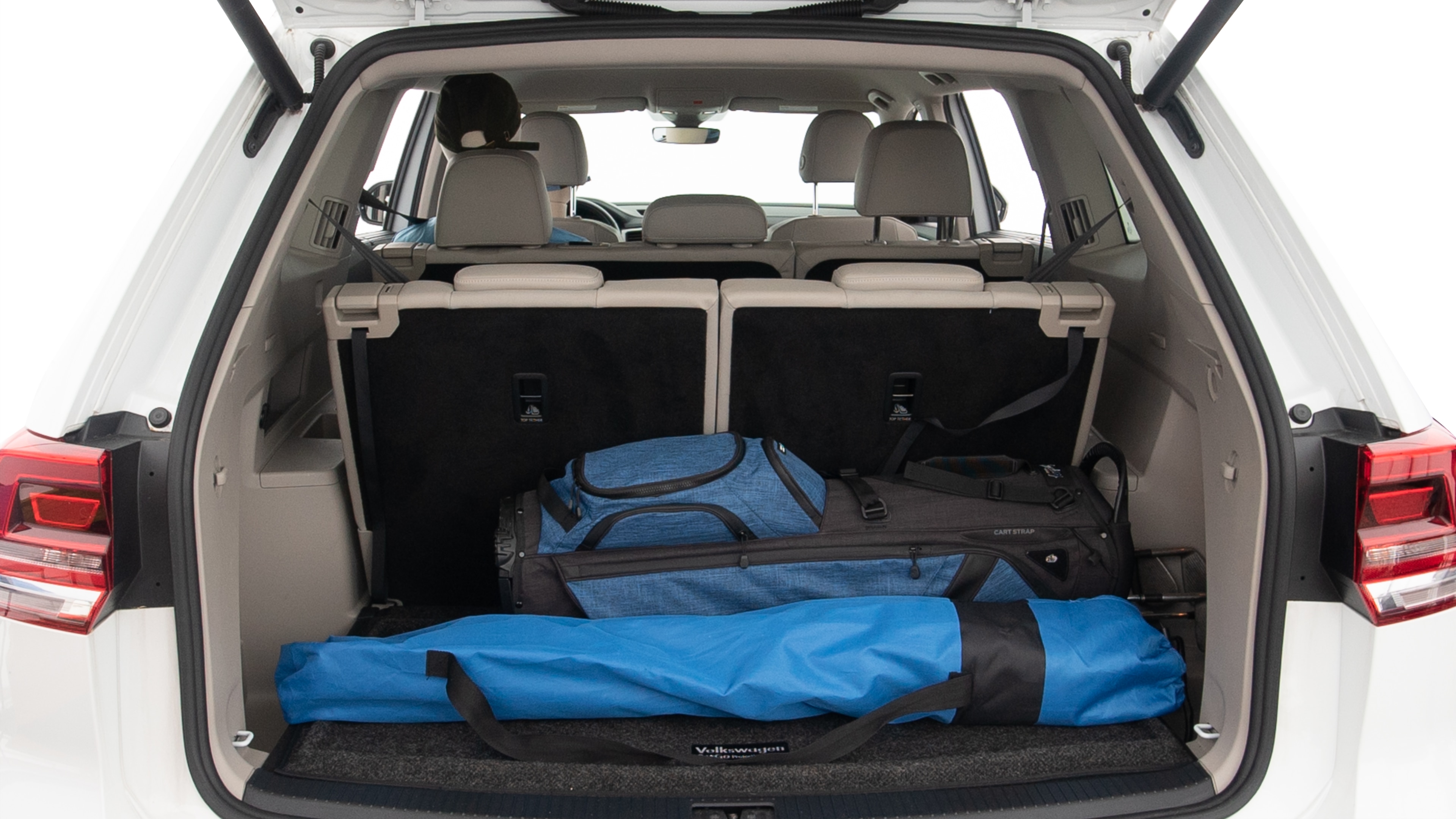 The trunk lid is open showing full view of the trunk. A baby stroller, three grocery carriers, two camping chairs in the carrying bag, and a set of golf clubs are placed inside.