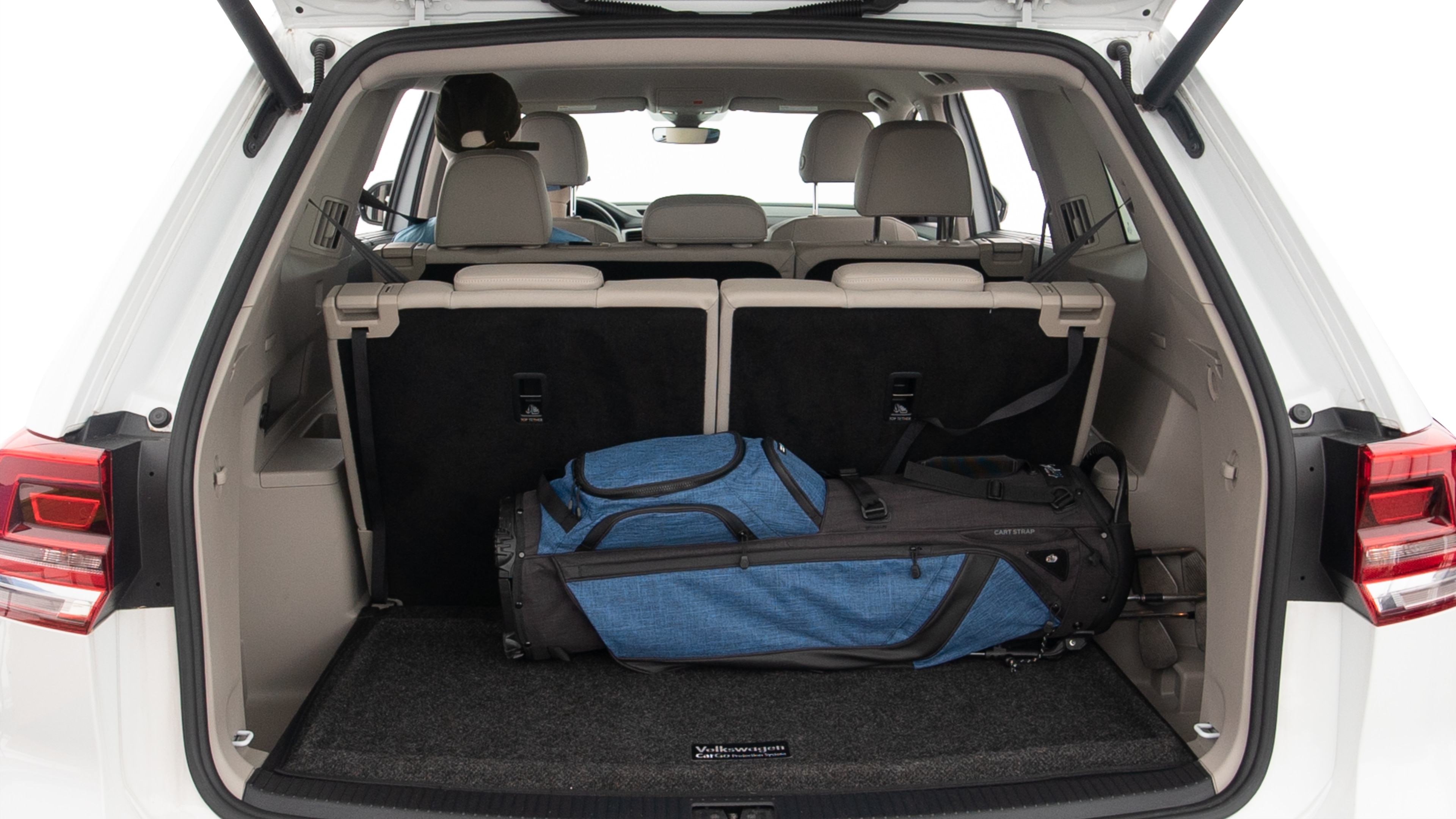 The trunk lid is open showing full view of the trunk. A baby stroller, three grocery carriers, two camping chairs in the carrying bag, and a set of golf clubs are placed inside.