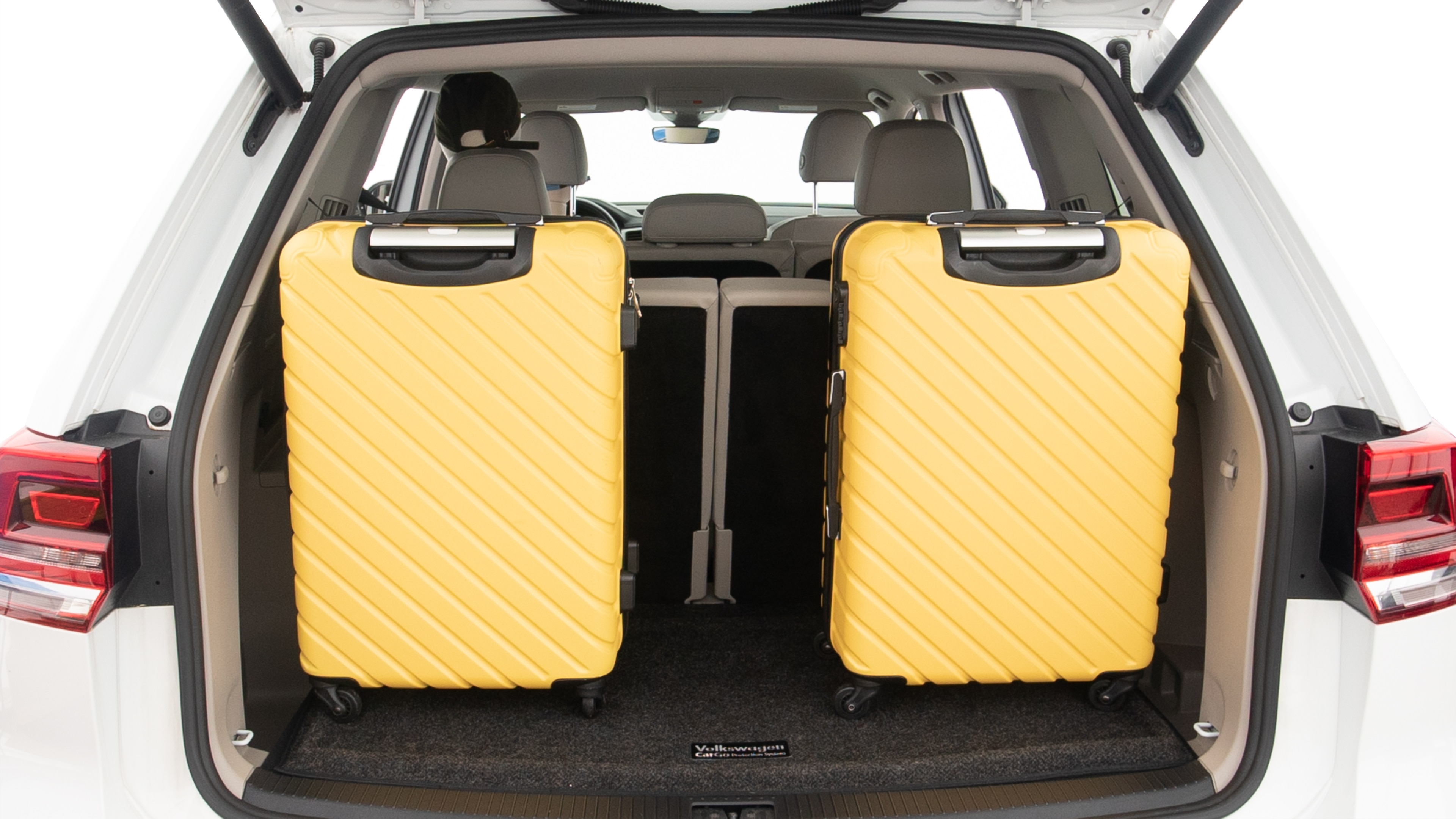 The trunk lid is open, showing full view of the trunk space. Two large and one small suitcases are placed inside.