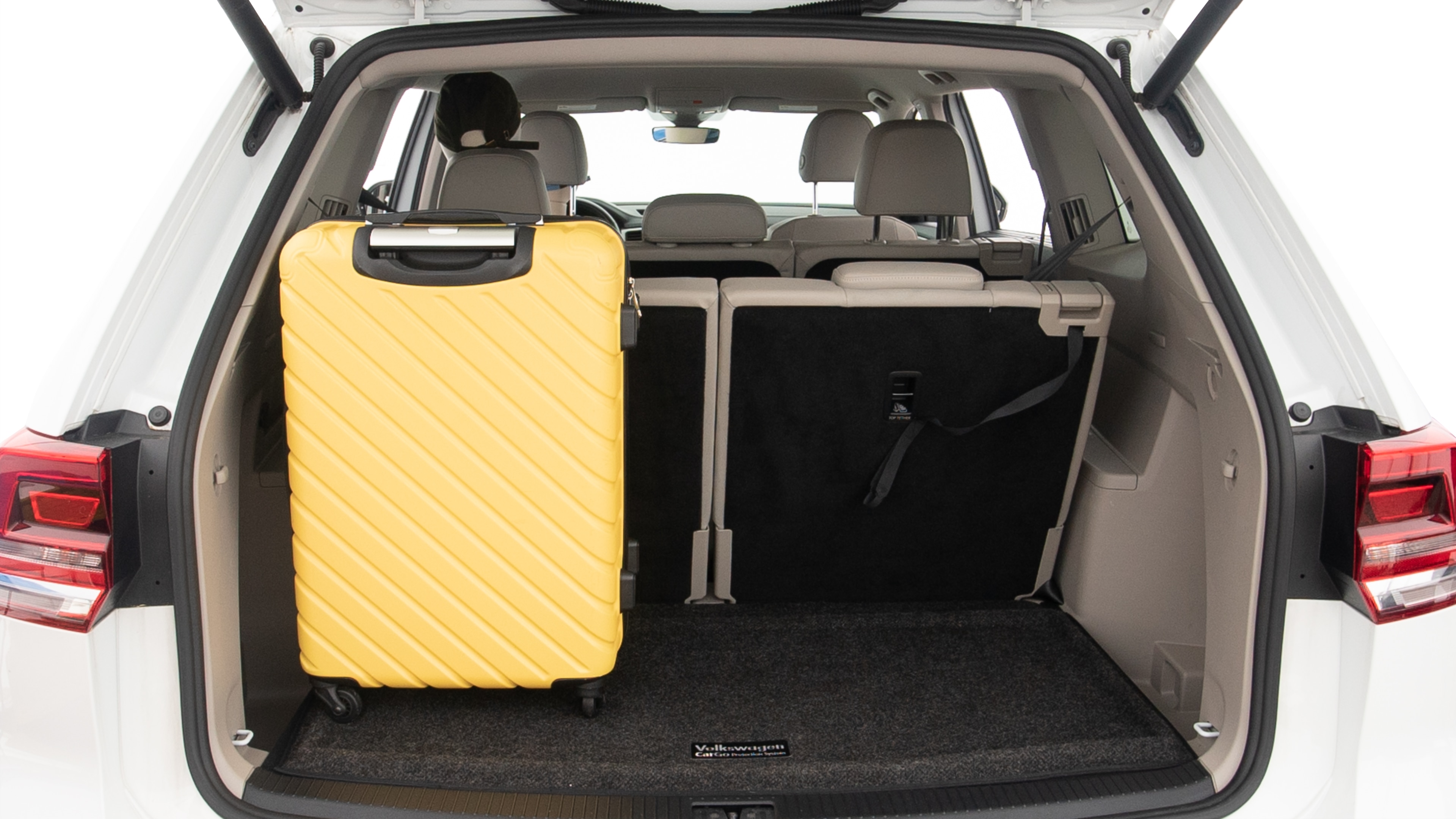 The trunk lid is open, showing full view of the trunk space. Two large and one small suitcases are placed inside.