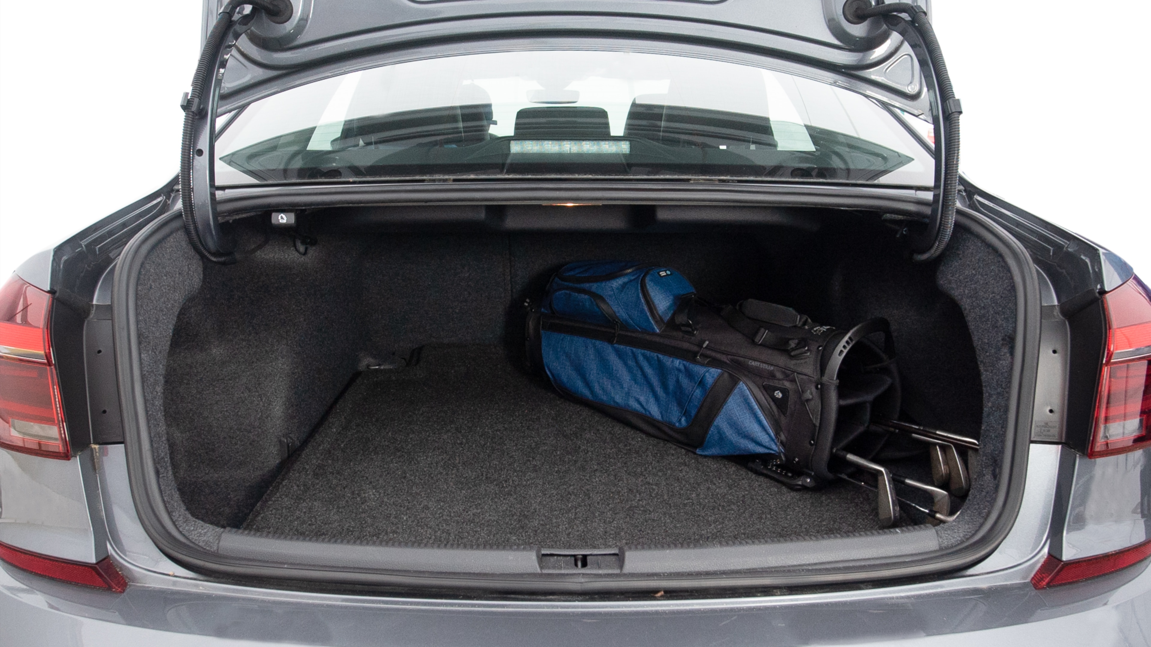 The trunk lid is open showing full view of the trunk. A baby stroller, three grocery carriers, two camping chairs in the carrying bag, and a set of golf clubs are placed inside.