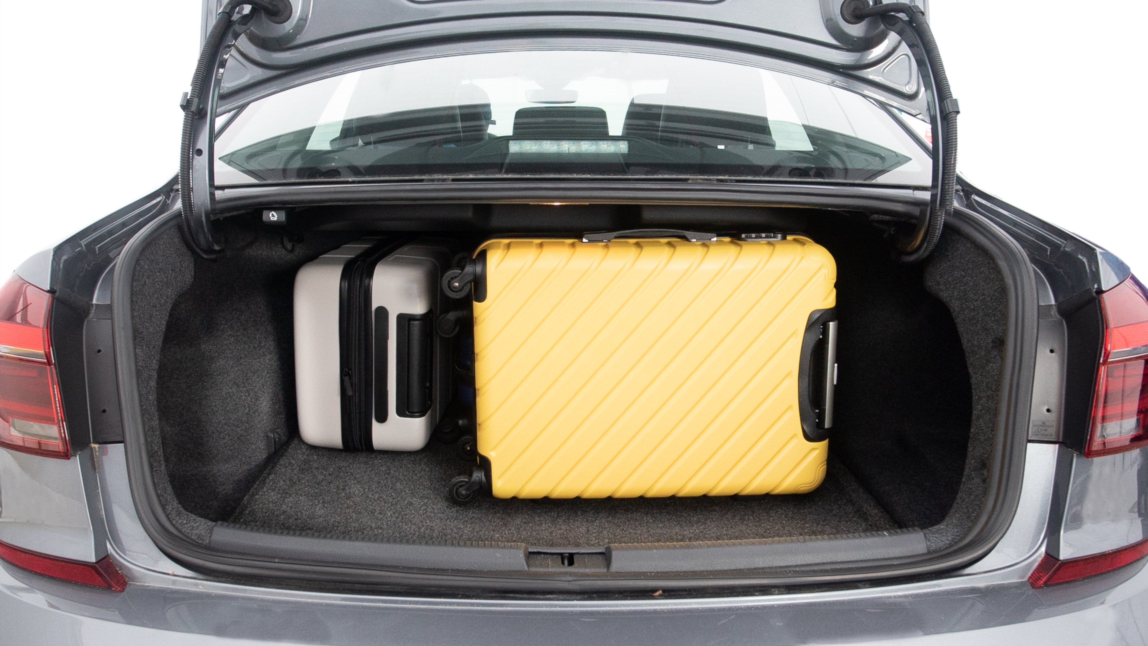 The trunk lid is open, showing full view of the trunk space. Three large and one small suitcases are placed inside.