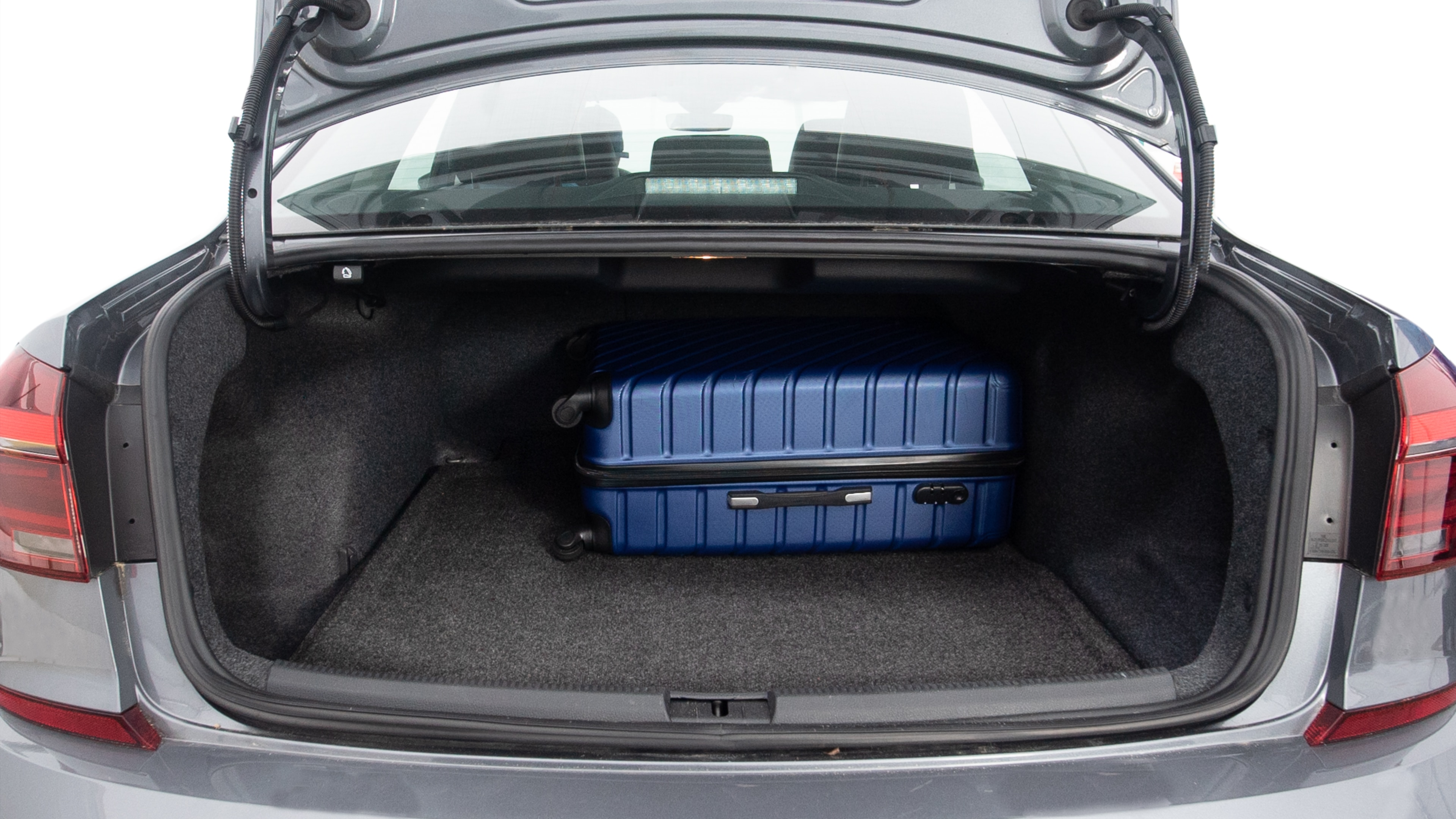 The trunk lid is open, showing full view of the trunk space. Three large and one small suitcases are placed inside.