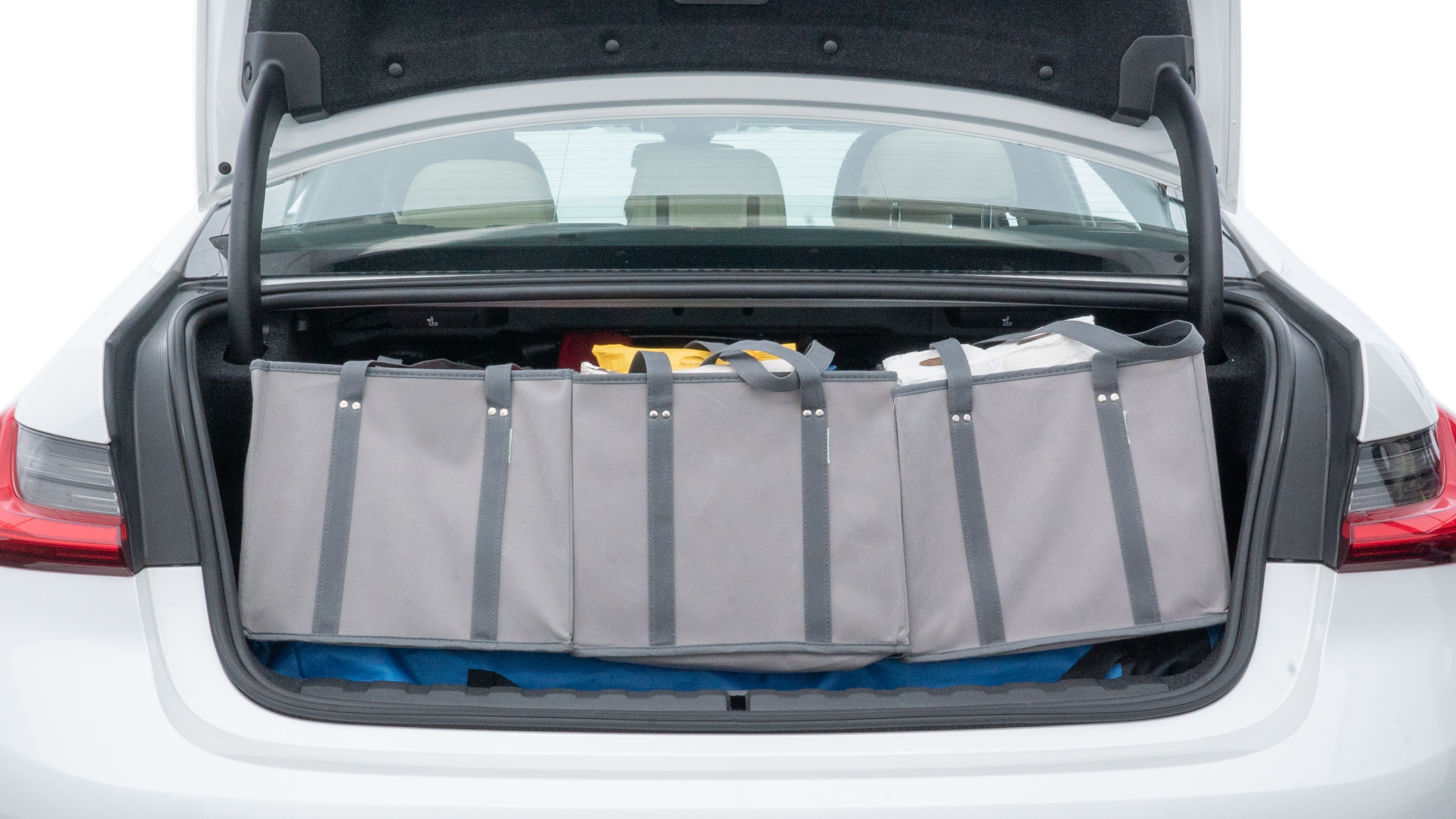 The trunk lid is open showing full view of the trunk. A baby stroller, three grocery carriers, two camping chairs in the carrying bag, and a set of golf clubs are placed inside.