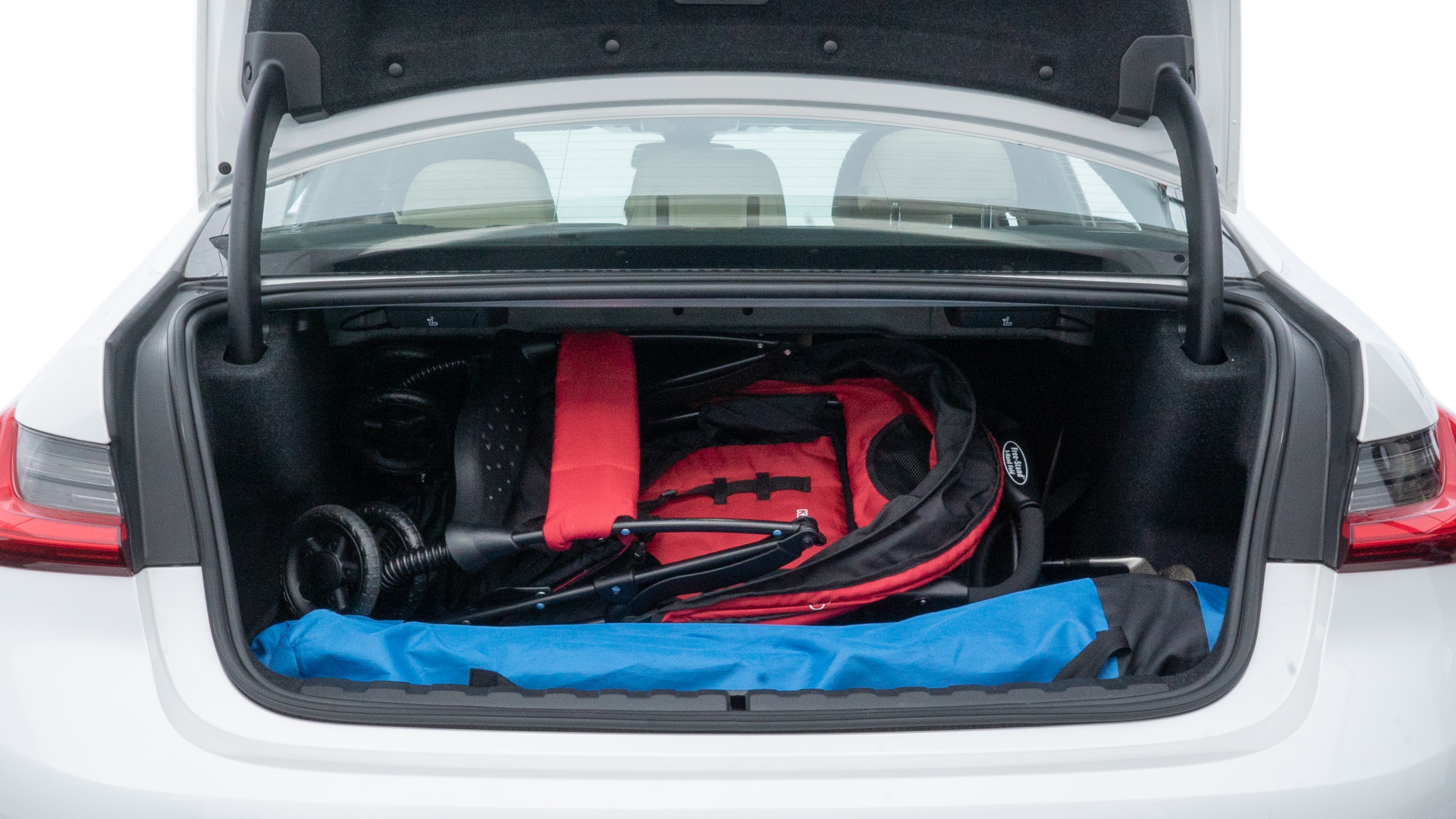 The trunk lid is open showing full view of the trunk. A baby stroller, three grocery carriers, two camping chairs in the carrying bag, and a set of golf clubs are placed inside.