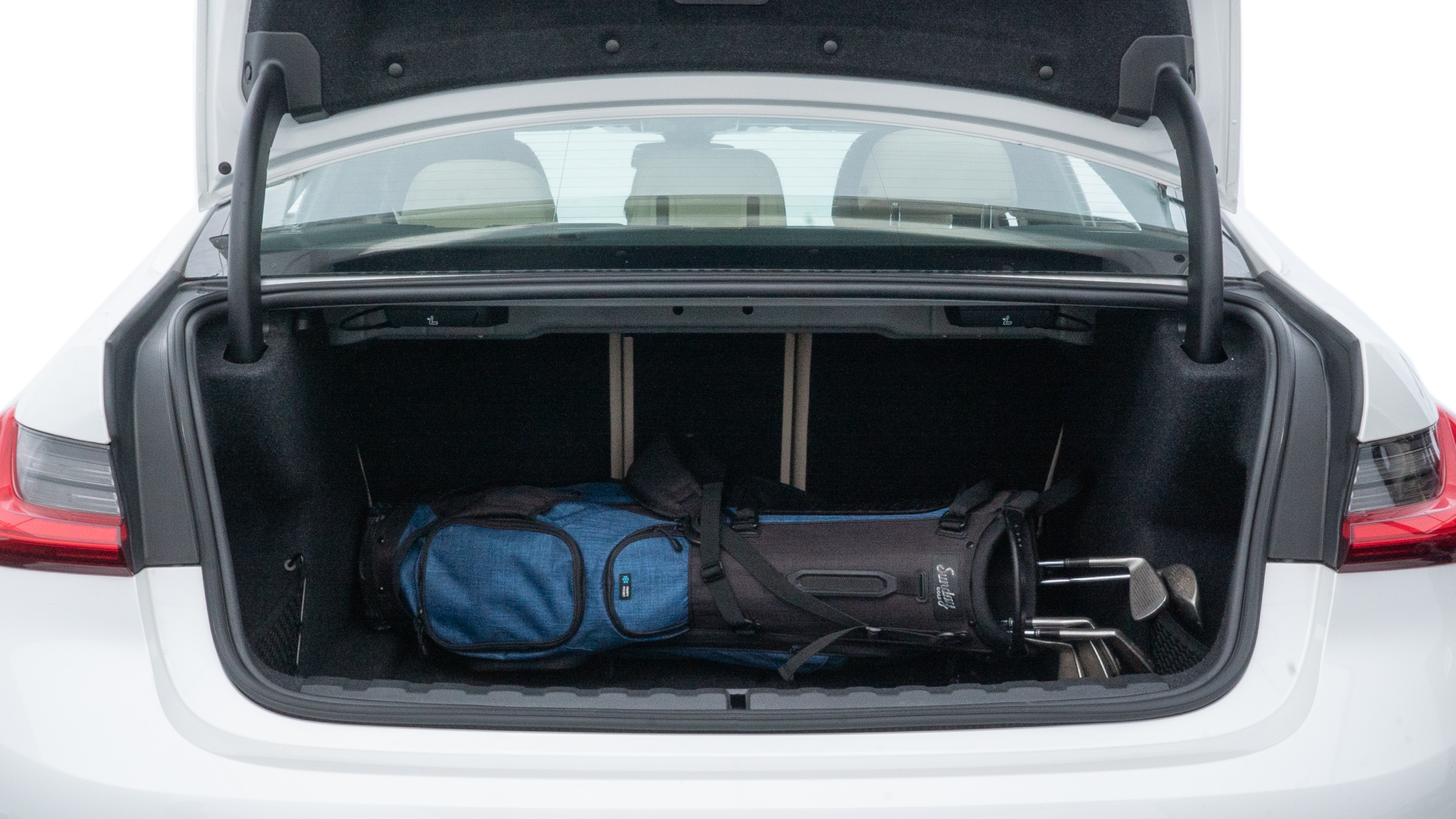 The trunk lid is open showing full view of the trunk. A baby stroller, three grocery carriers, two camping chairs in the carrying bag, and a set of golf clubs are placed inside.