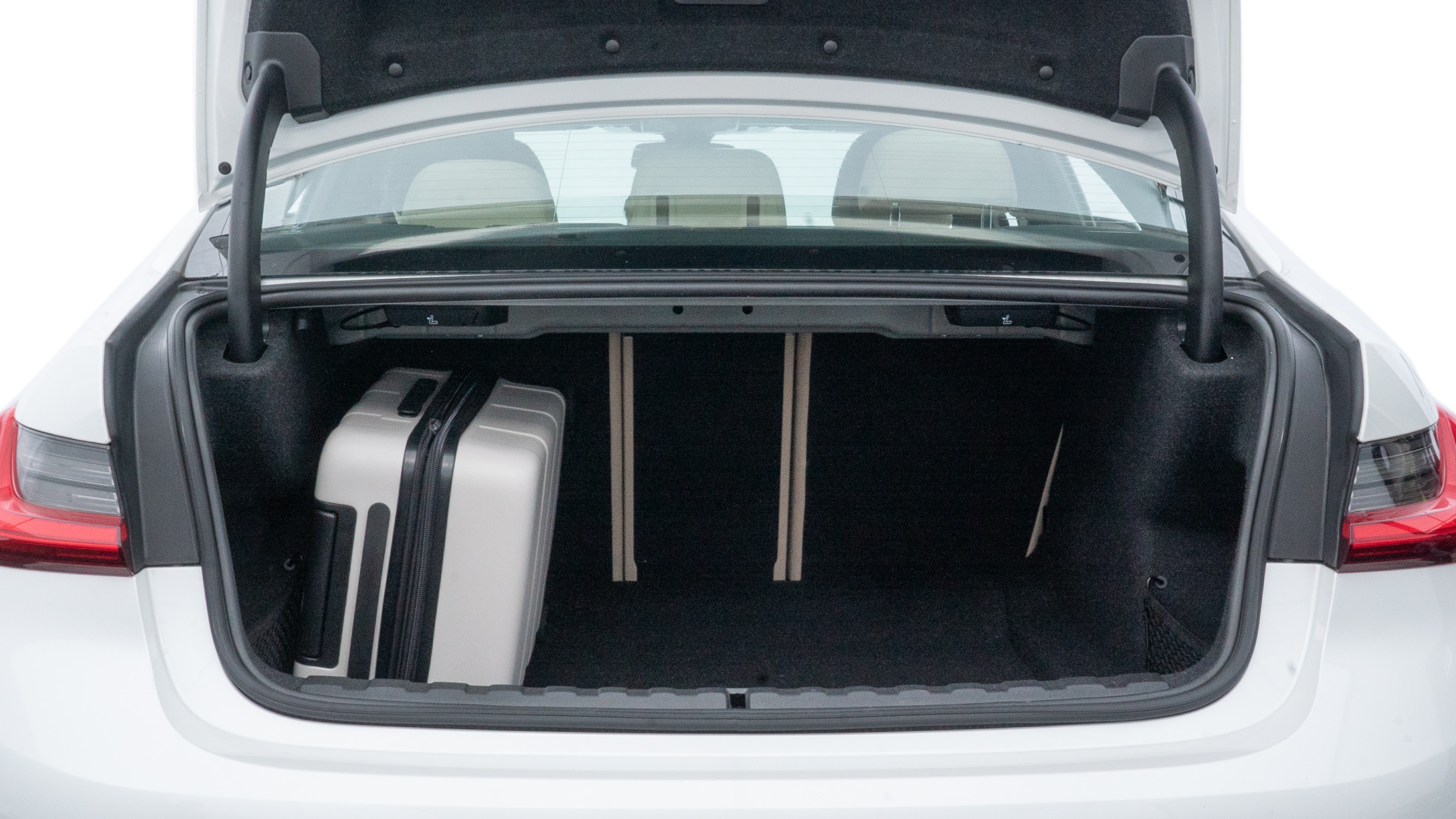 The trunk lid is open, showing full view of the trunk space. One large, two medium, and two small suitcases are placed inside.