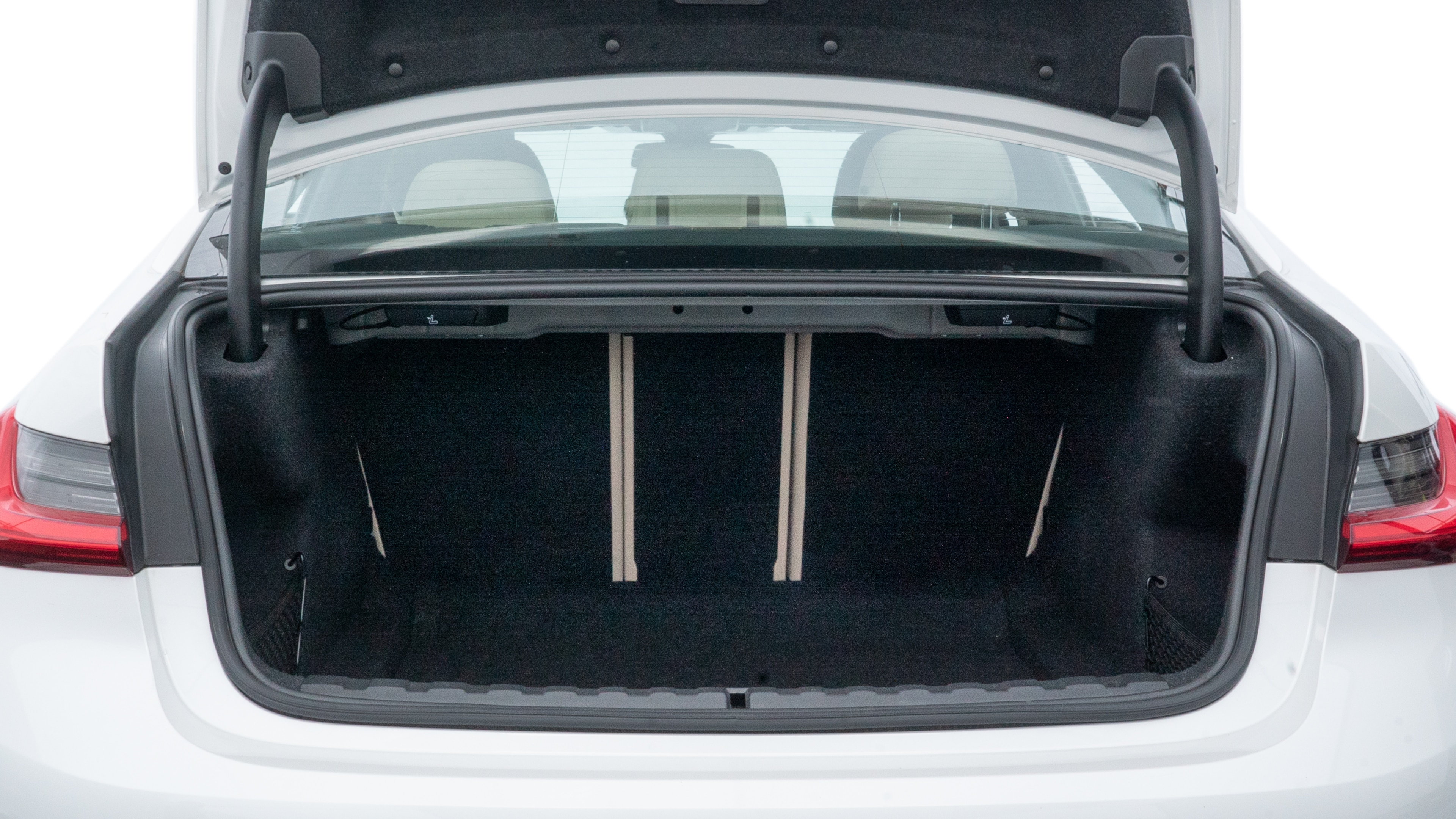 The trunk lid is open, showing full view of the trunk space. One large, two medium, and two small suitcases are placed inside.