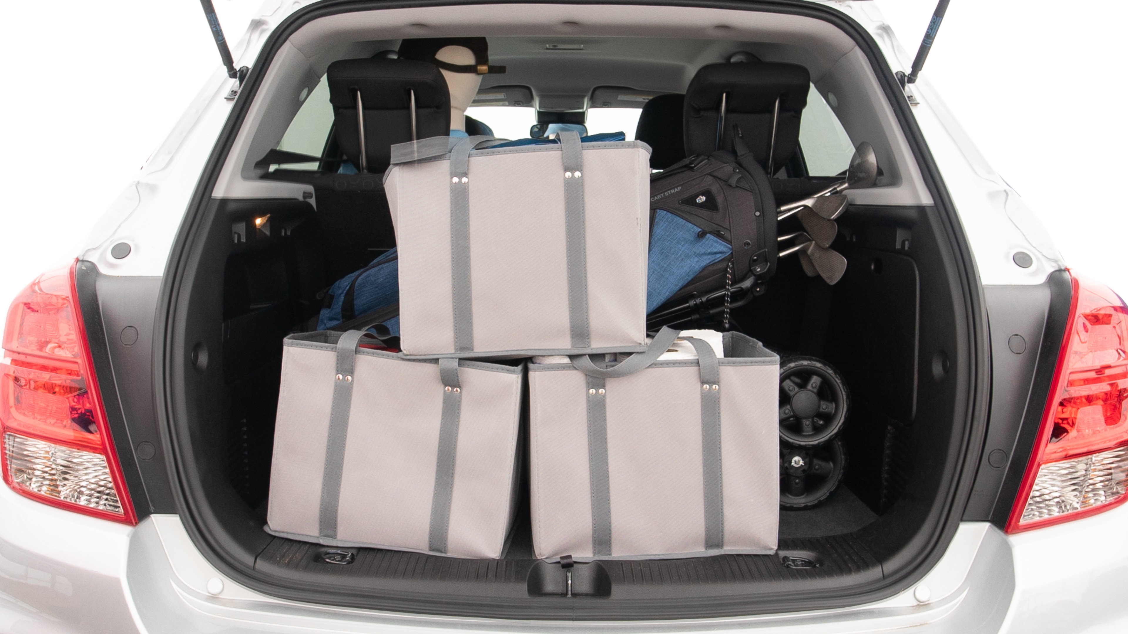The trunk lid is open showing full view of the trunk. A baby stroller, three grocery carriers and a set of golf clubs are placed inside.