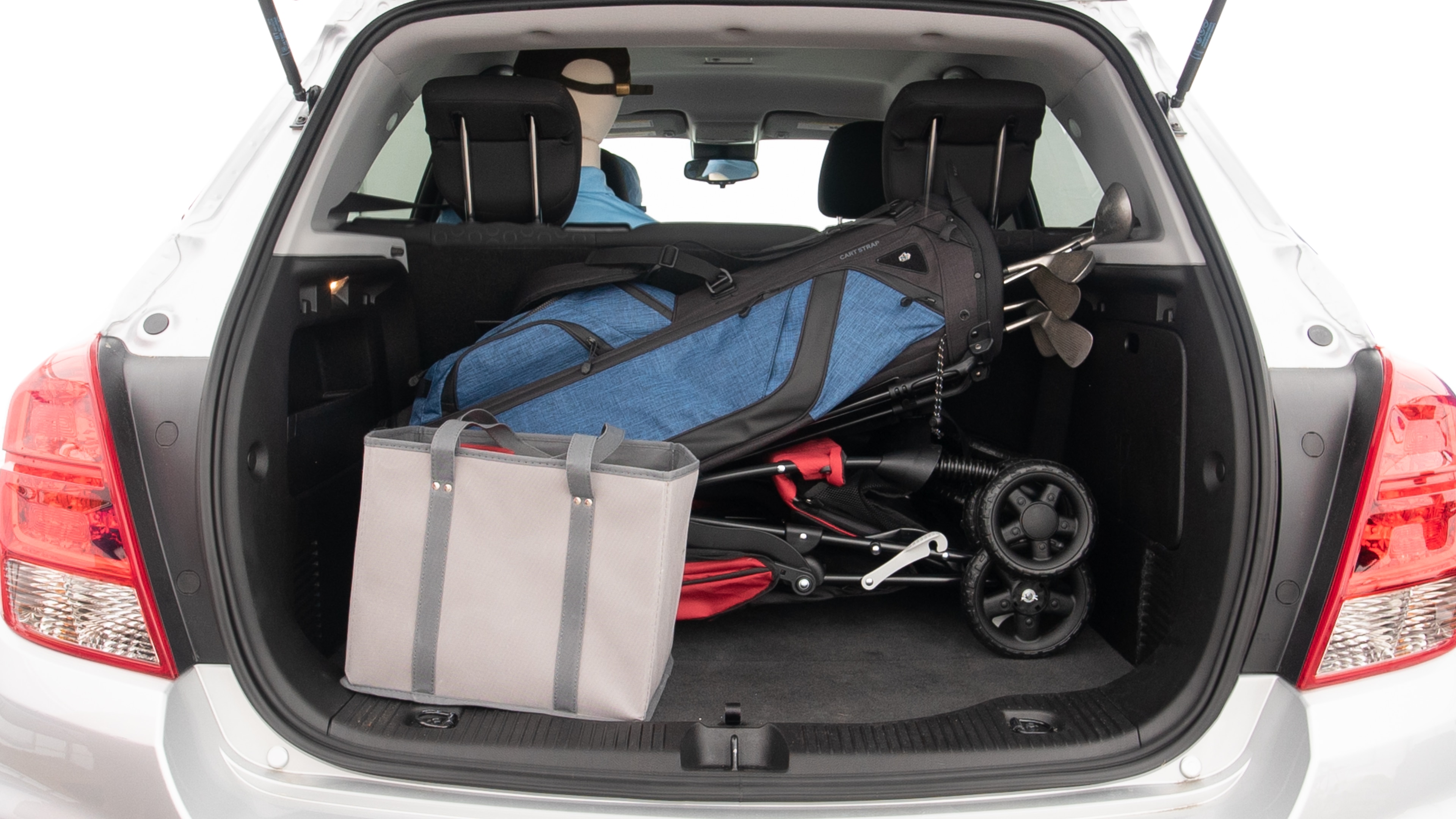 The trunk lid is open showing full view of the trunk. A baby stroller, three grocery carriers and a set of golf clubs are placed inside.