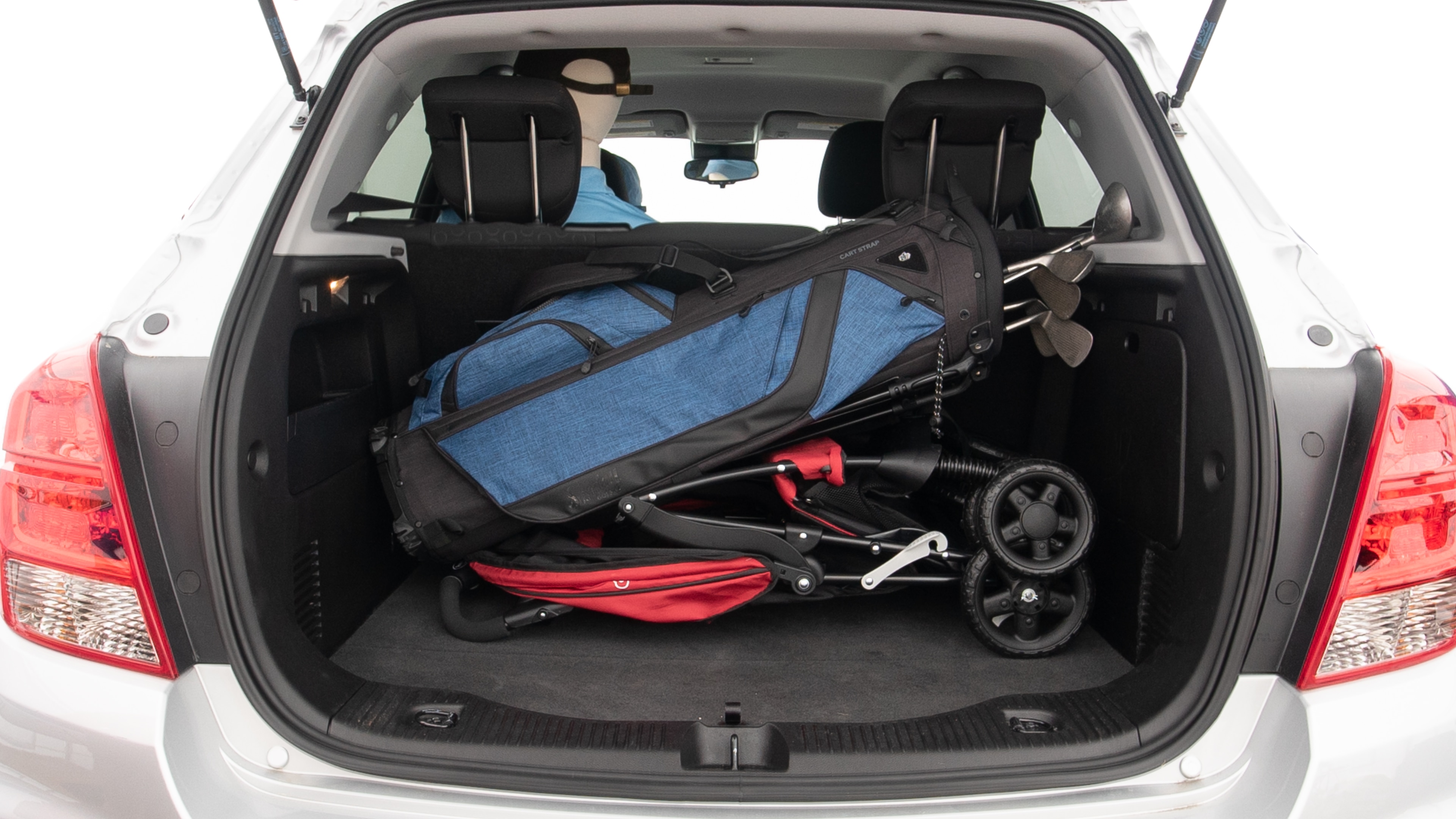 The trunk lid is open showing full view of the trunk. A baby stroller, three grocery carriers and a set of golf clubs are placed inside.