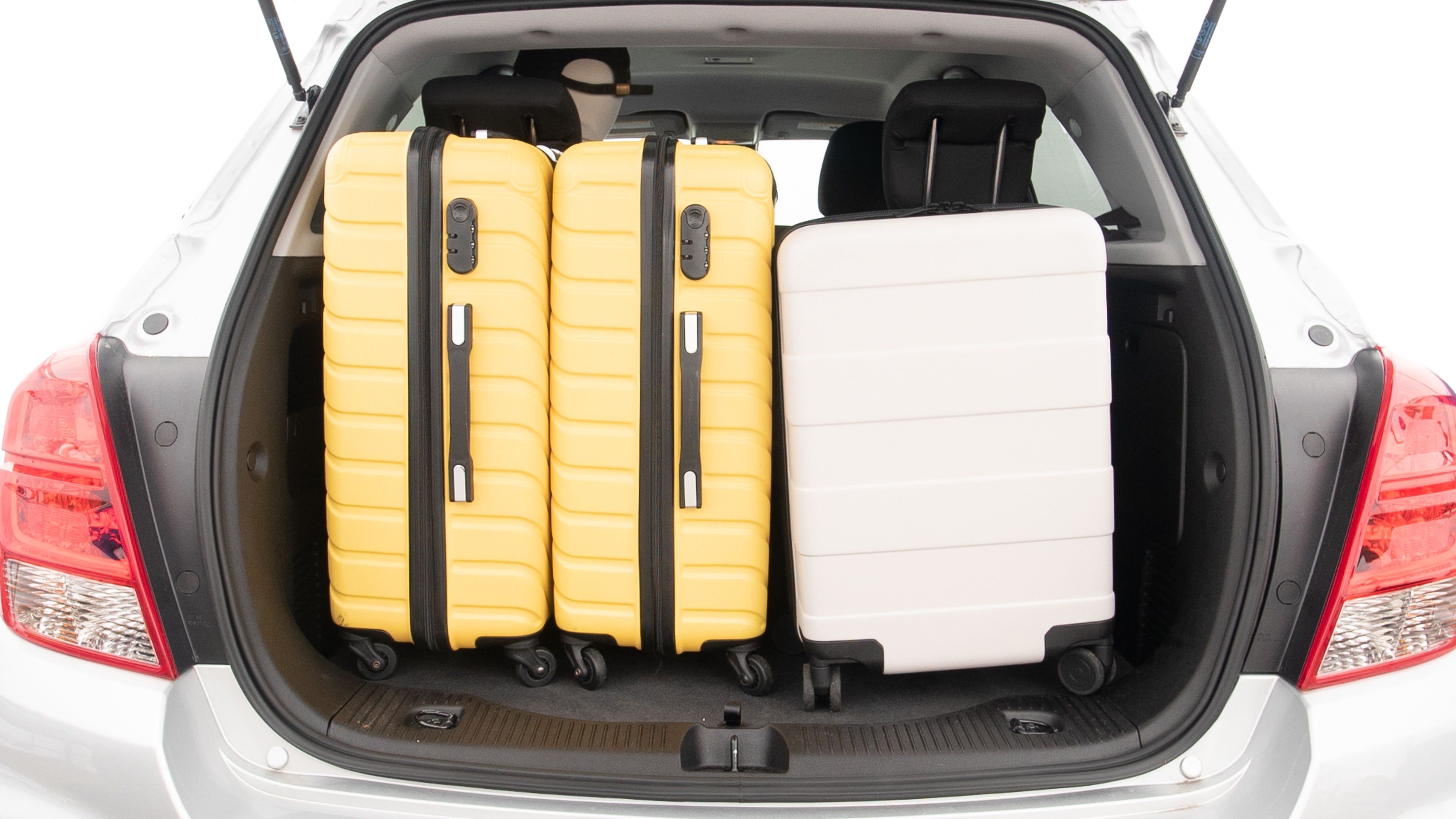 The trunk lid is open, showing full view of the trunk space. Two large and two small suitcases are placed inside.