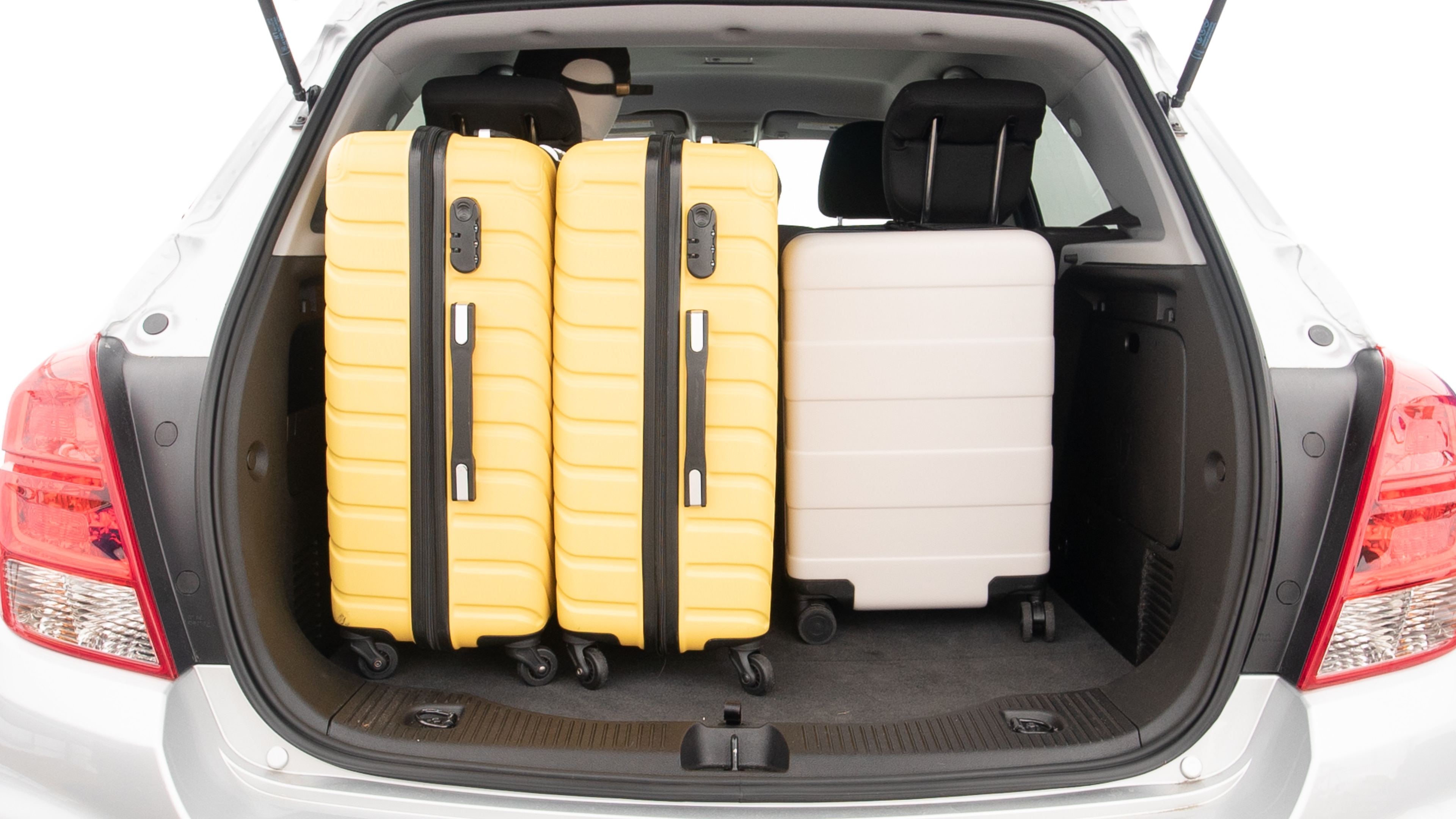 The trunk lid is open, showing full view of the trunk space. Two large and two small suitcases are placed inside.