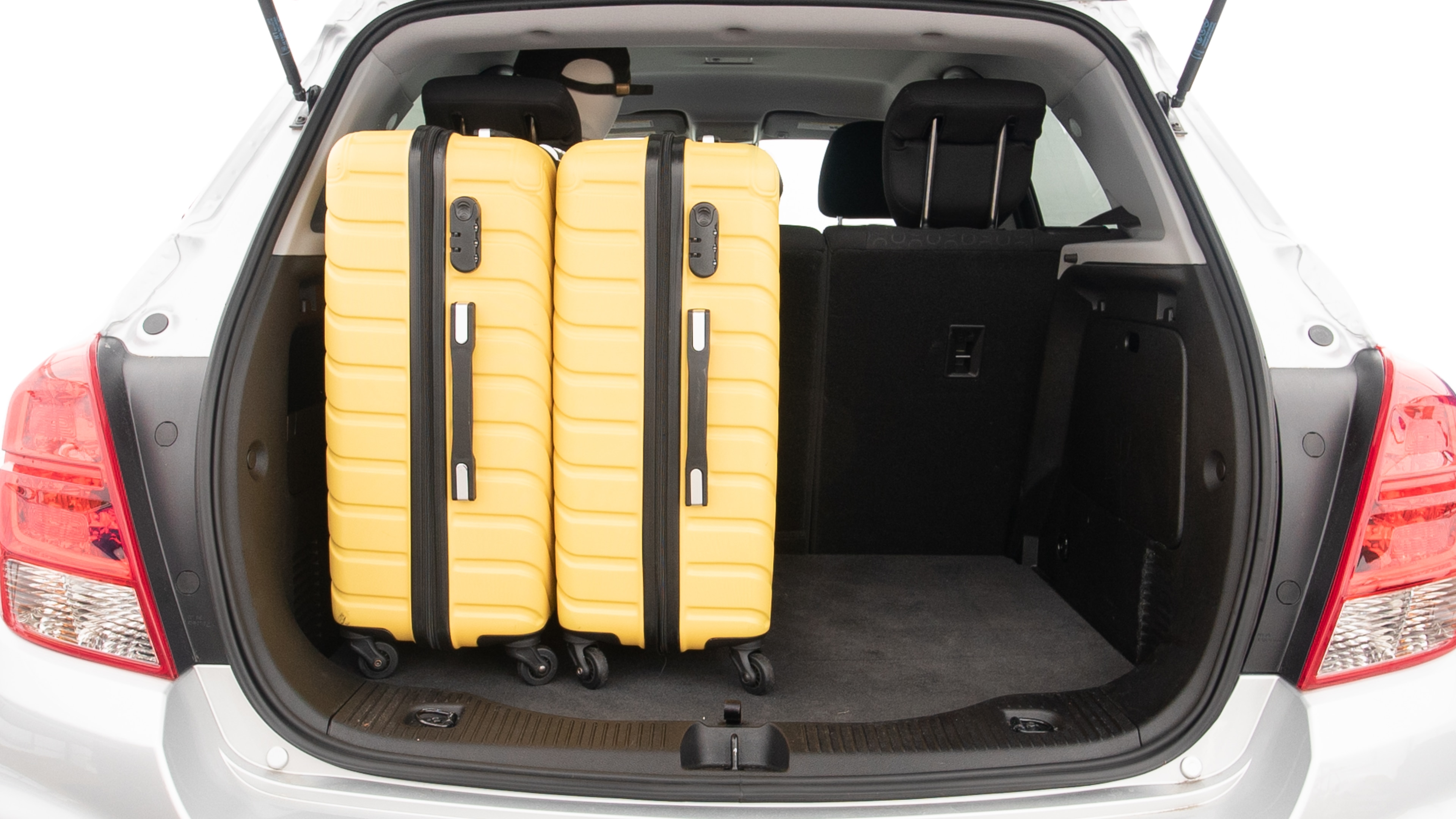 The trunk lid is open, showing full view of the trunk space. Two large and two small suitcases are placed inside.