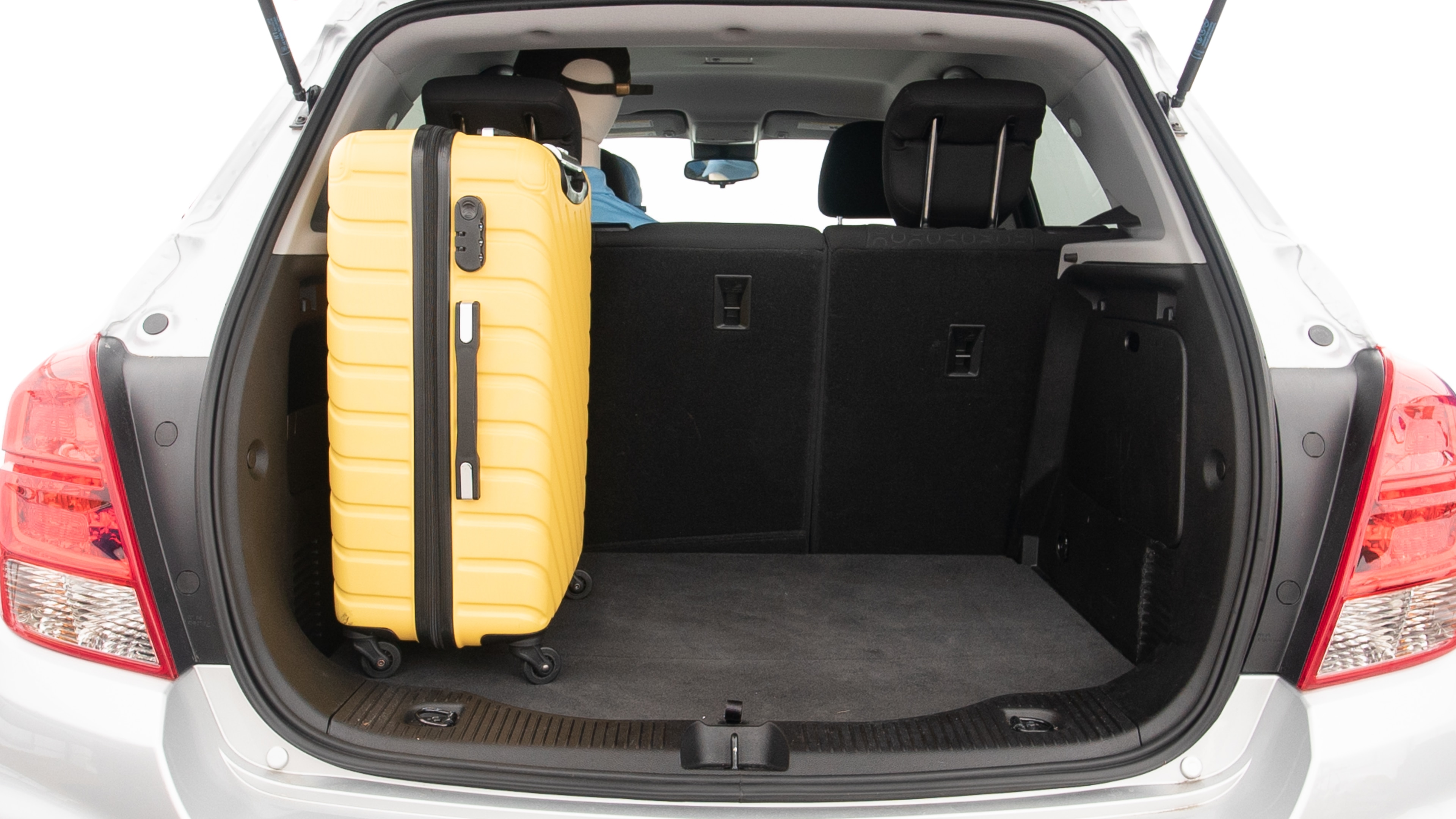 The trunk lid is open, showing full view of the trunk space. Two large and two small suitcases are placed inside.
