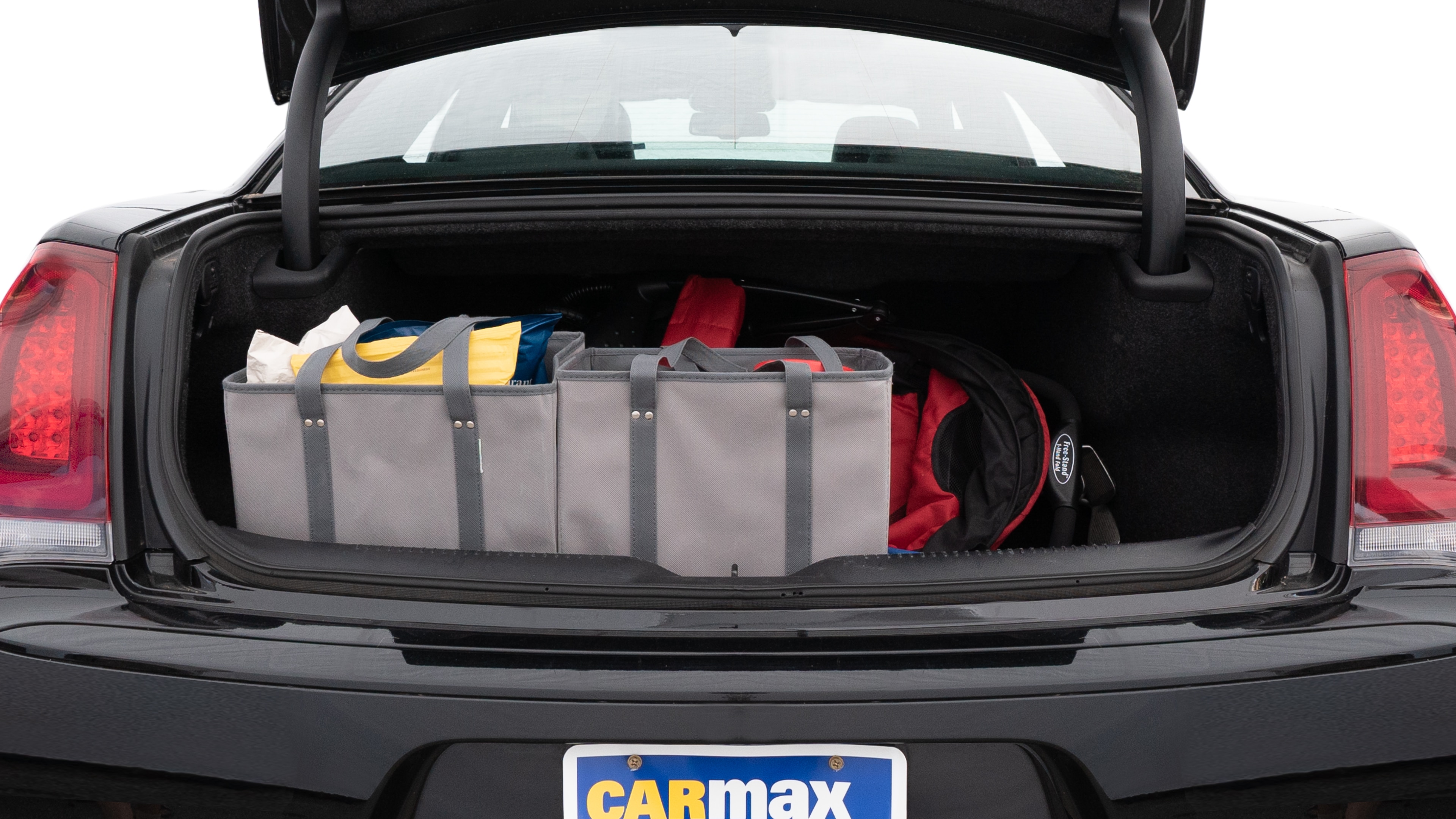 The trunk lid is open showing full view of the trunk. A baby stroller, three grocery carriers, two camping chairs in the carrying bag, and a set of golf clubs are placed inside.