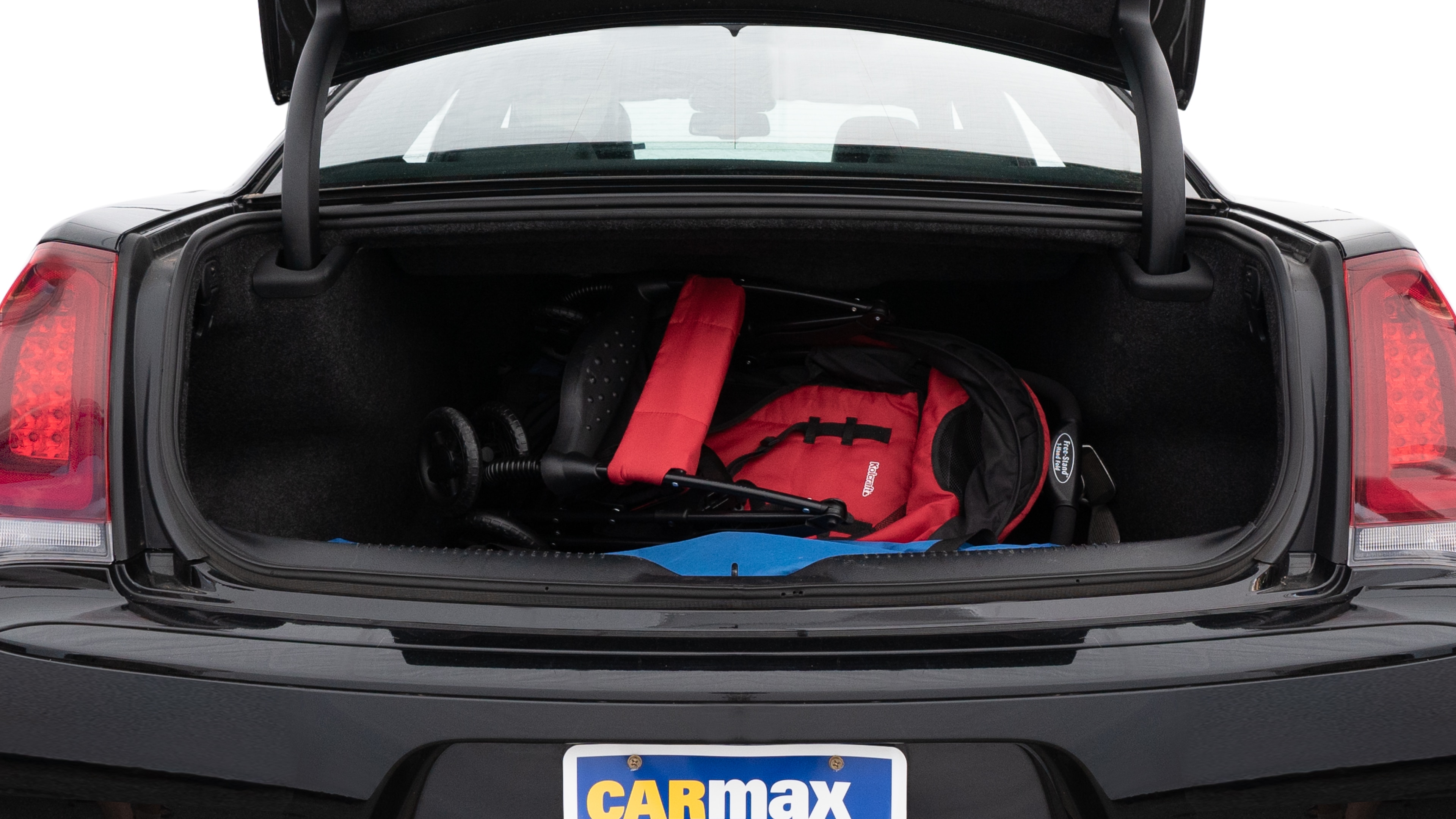 The trunk lid is open showing full view of the trunk. A baby stroller, three grocery carriers, two camping chairs in the carrying bag, and a set of golf clubs are placed inside.