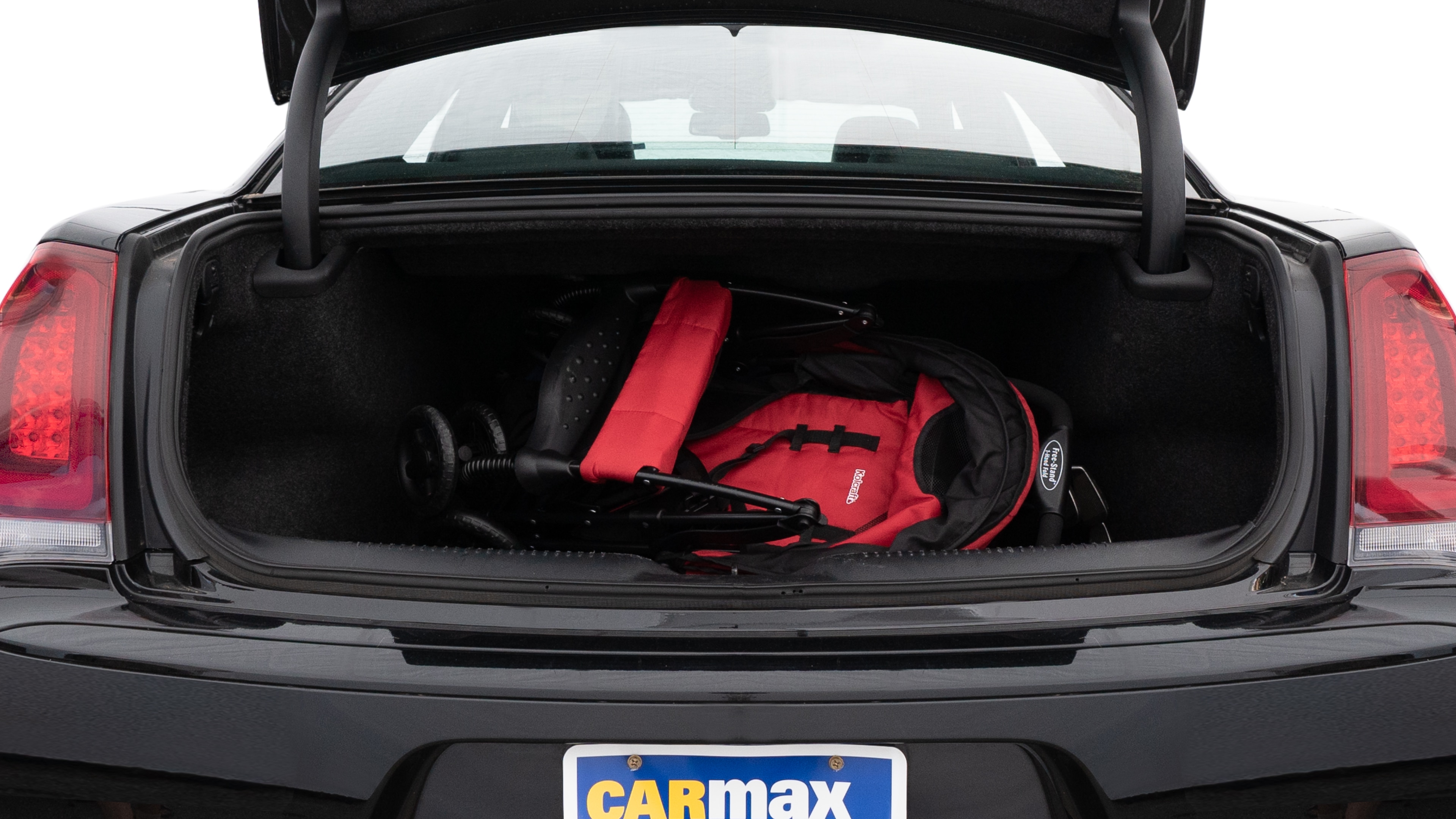 The trunk lid is open showing full view of the trunk. A baby stroller, three grocery carriers, two camping chairs in the carrying bag, and a set of golf clubs are placed inside.