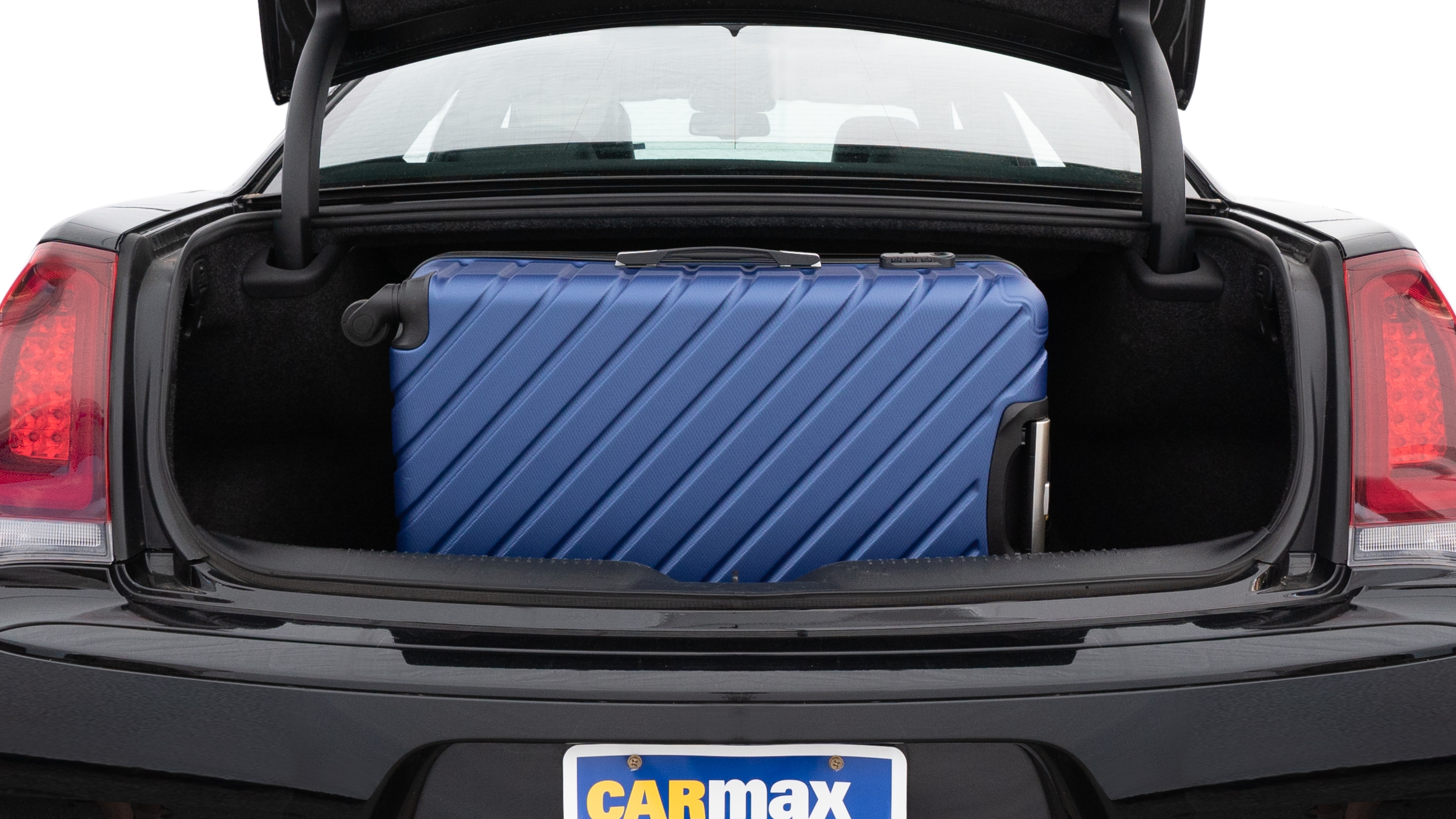 The trunk lid is open, showing full view of the trunk space. One large and two medium suitcases are placed inside.