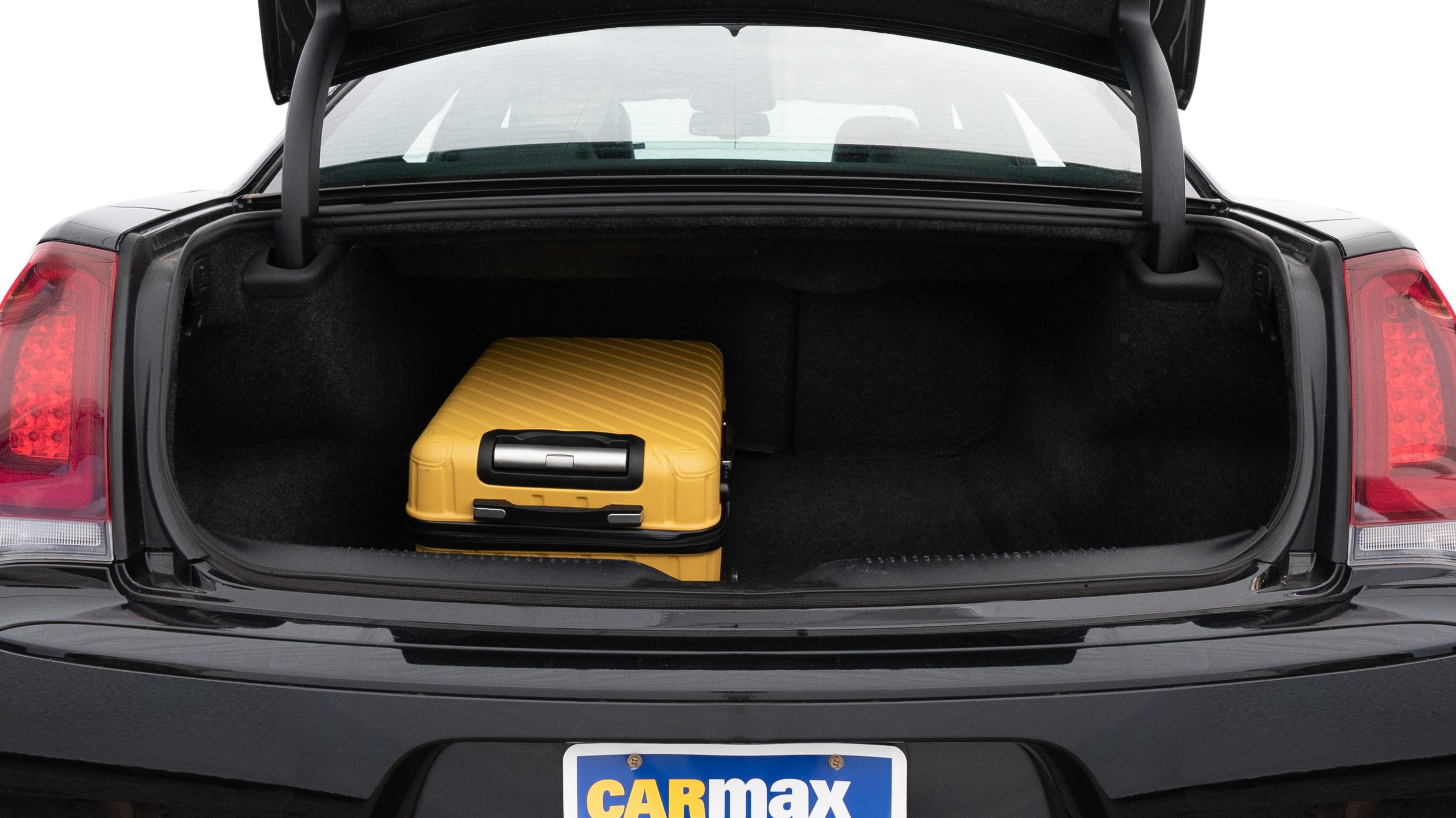 The trunk lid is open, showing full view of the trunk space. One large and two medium suitcases are placed inside.