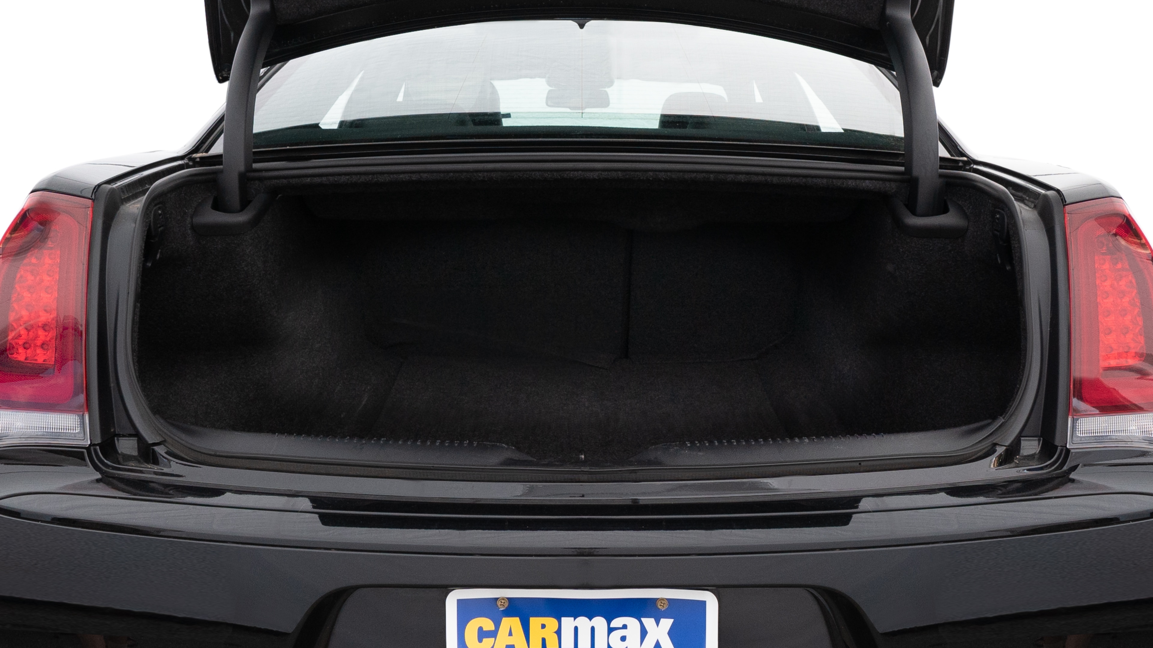 The trunk lid is open, showing full view of the trunk space. One large and two medium suitcases are placed inside.