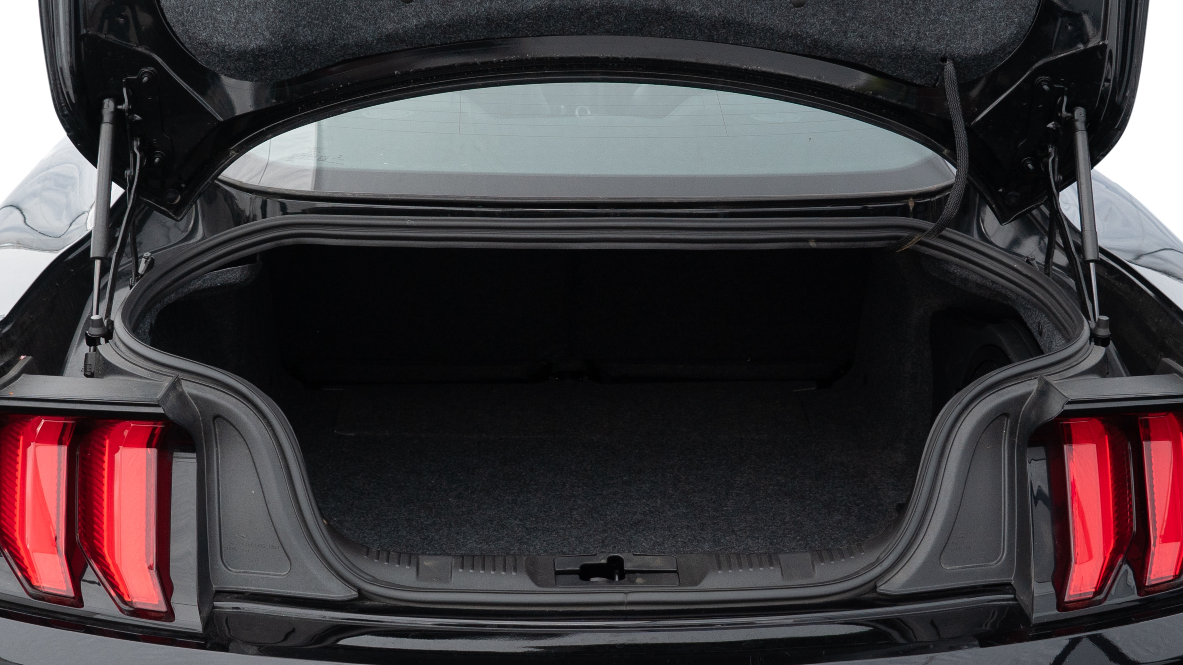 The trunk lid is open, showing full view of the trunk space. One large, one medium, and one small suitcase are placed inside.
