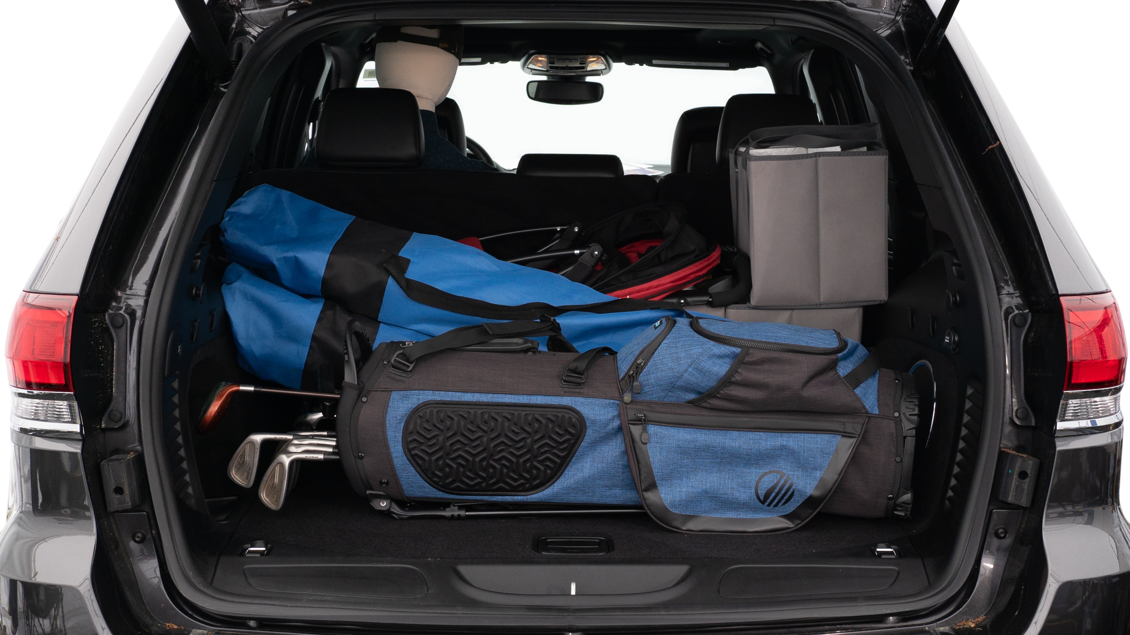 The trunk lid is open showing full view of the trunk. A baby stroller, three grocery carriers, two camping chairs in the carrying bag, and a set of golf clubs are placed inside.