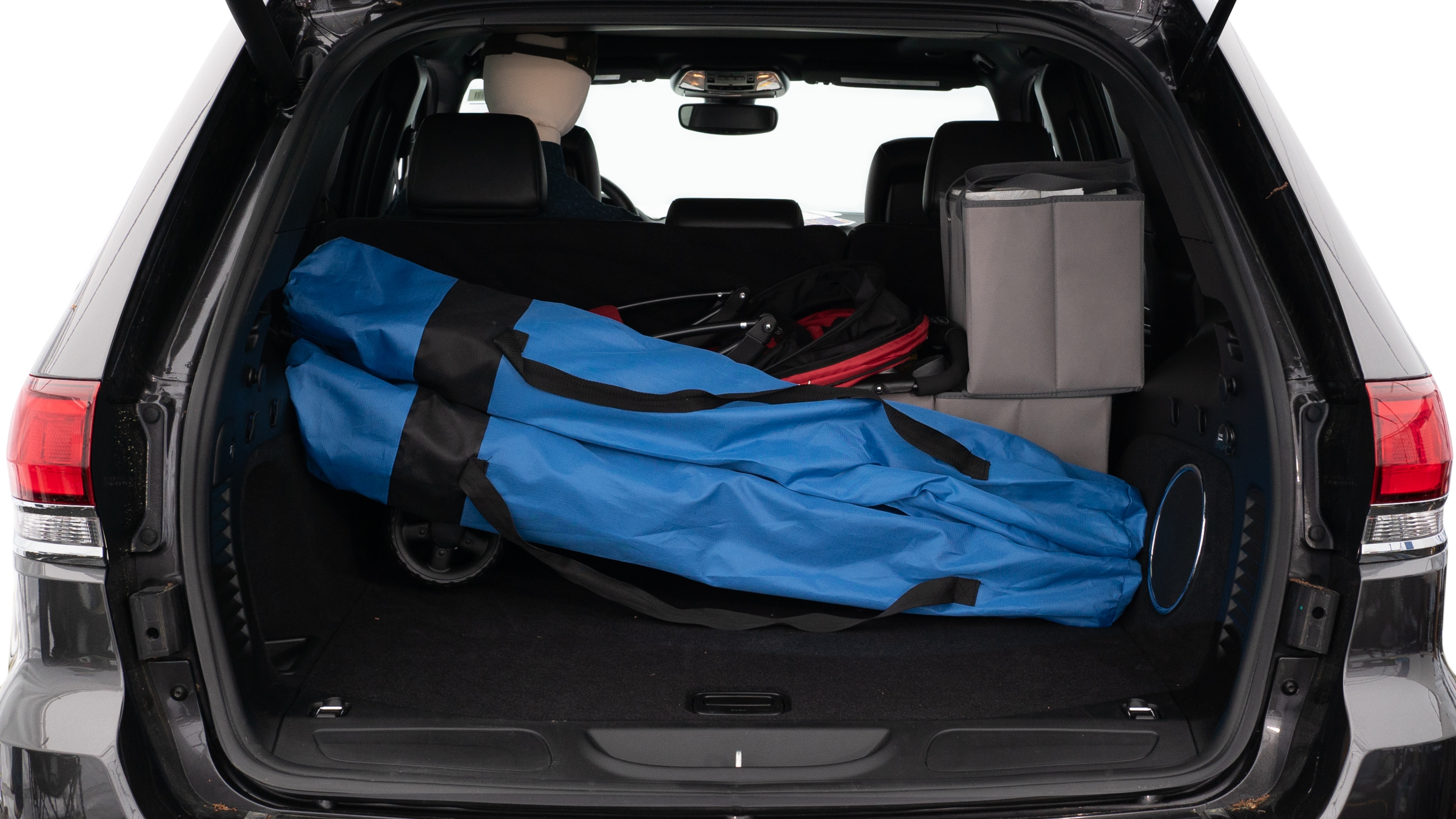 The trunk lid is open showing full view of the trunk. A baby stroller, three grocery carriers, two camping chairs in the carrying bag, and a set of golf clubs are placed inside.