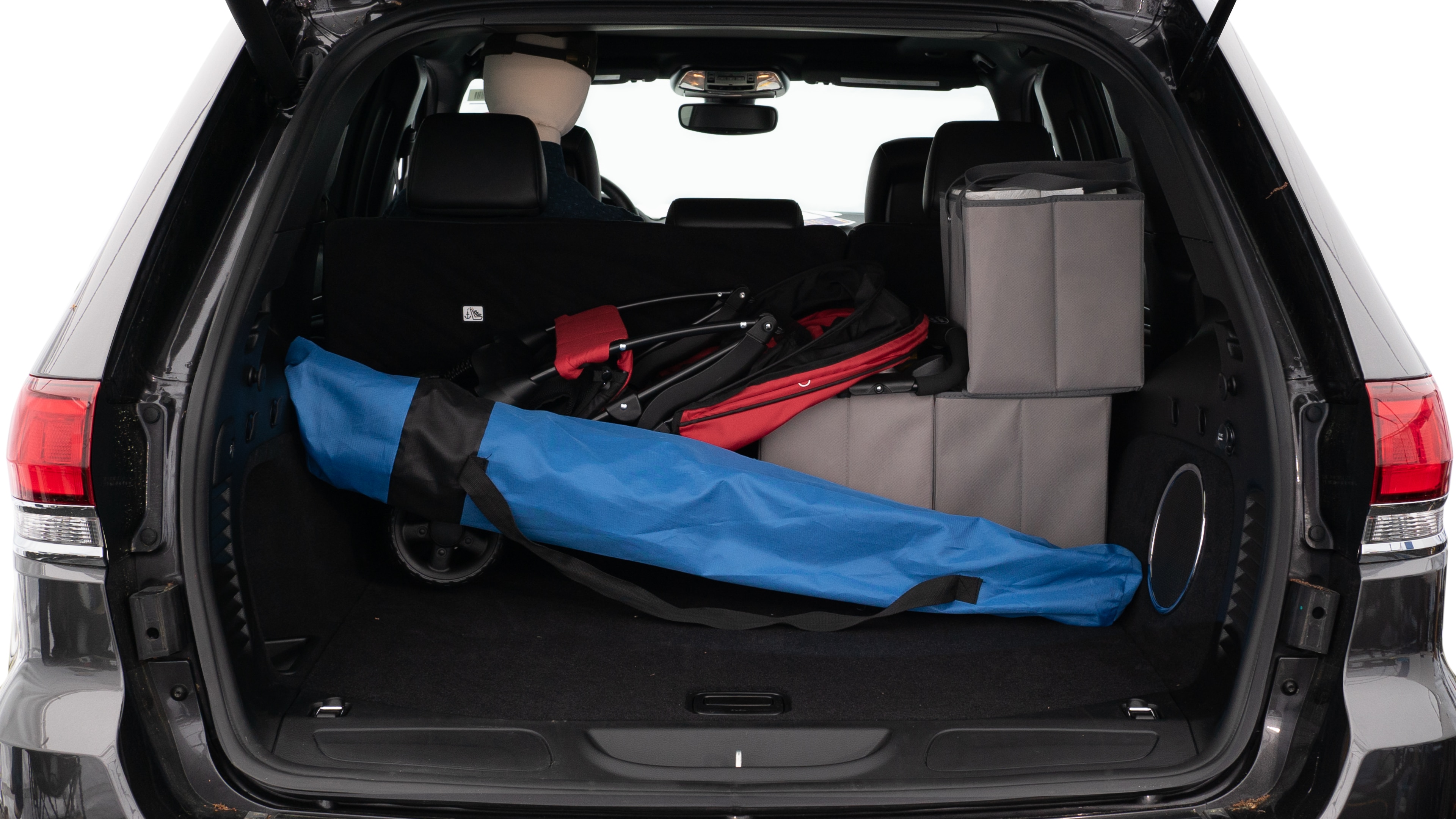 The trunk lid is open showing full view of the trunk. A baby stroller, three grocery carriers, two camping chairs in the carrying bag, and a set of golf clubs are placed inside.