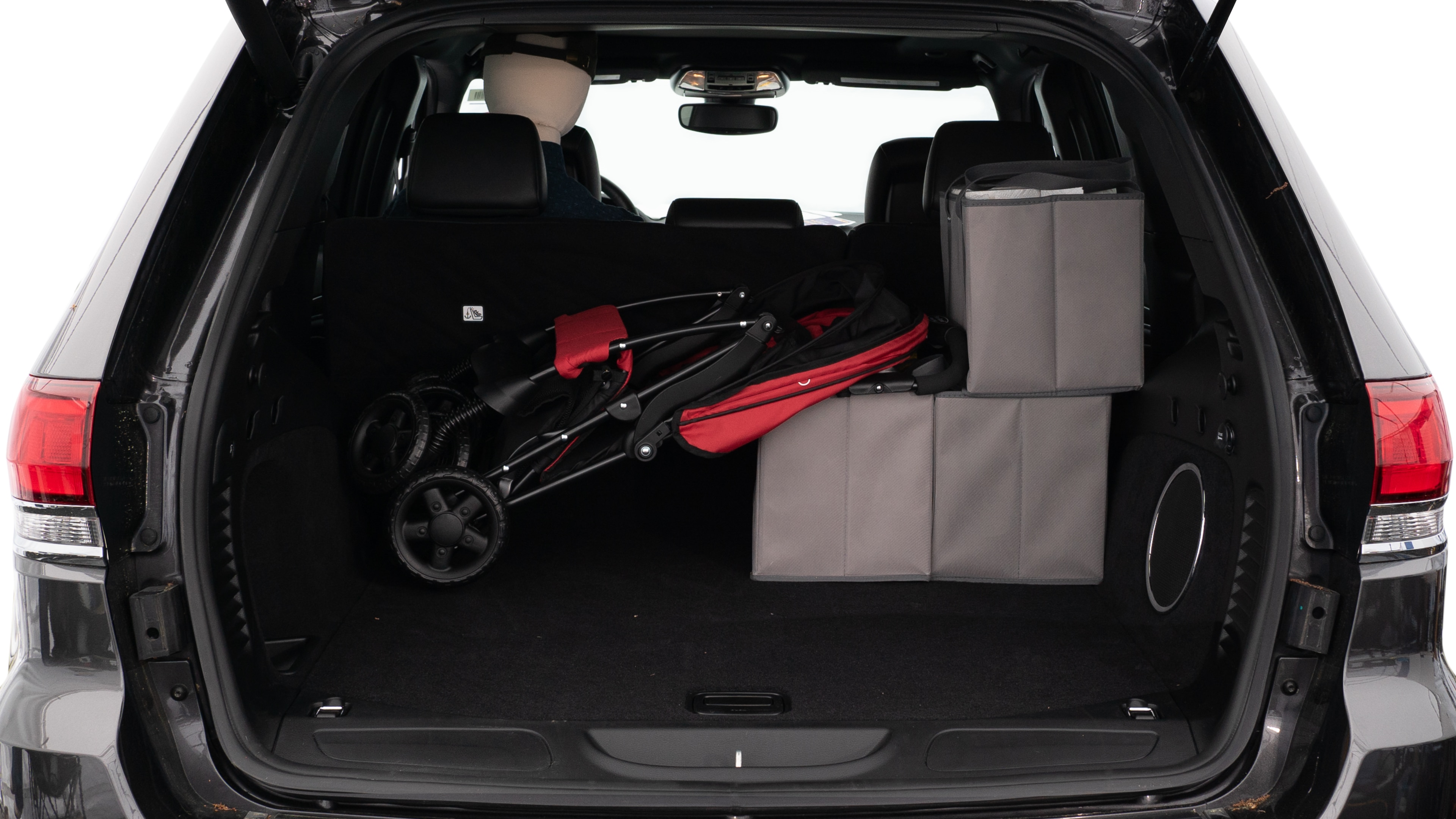 The trunk lid is open showing full view of the trunk. A baby stroller, three grocery carriers, two camping chairs in the carrying bag, and a set of golf clubs are placed inside.