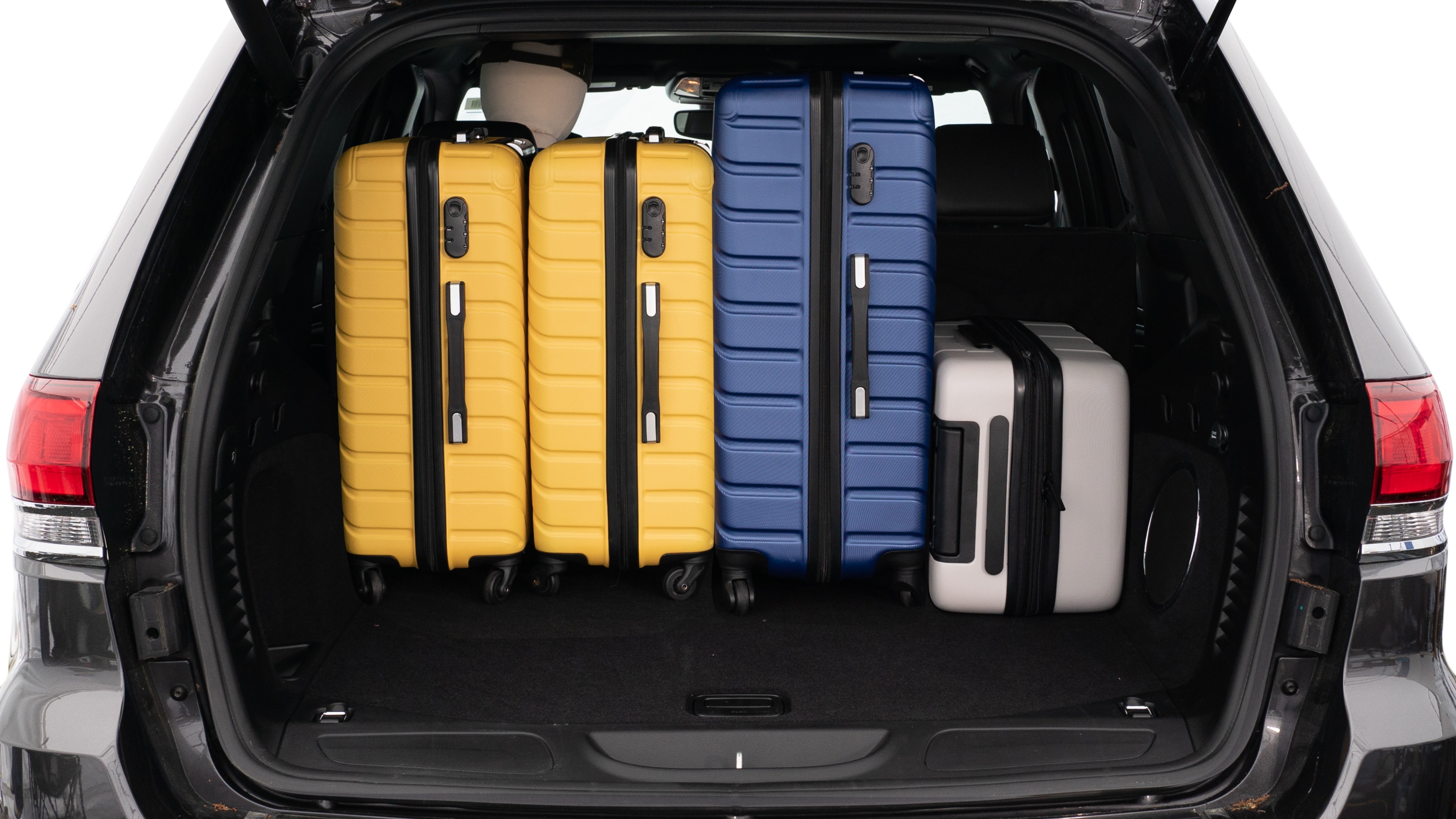 The trunk lid is open, showing a full view of the trunk space. Three large and two small suitcases are placed on there side