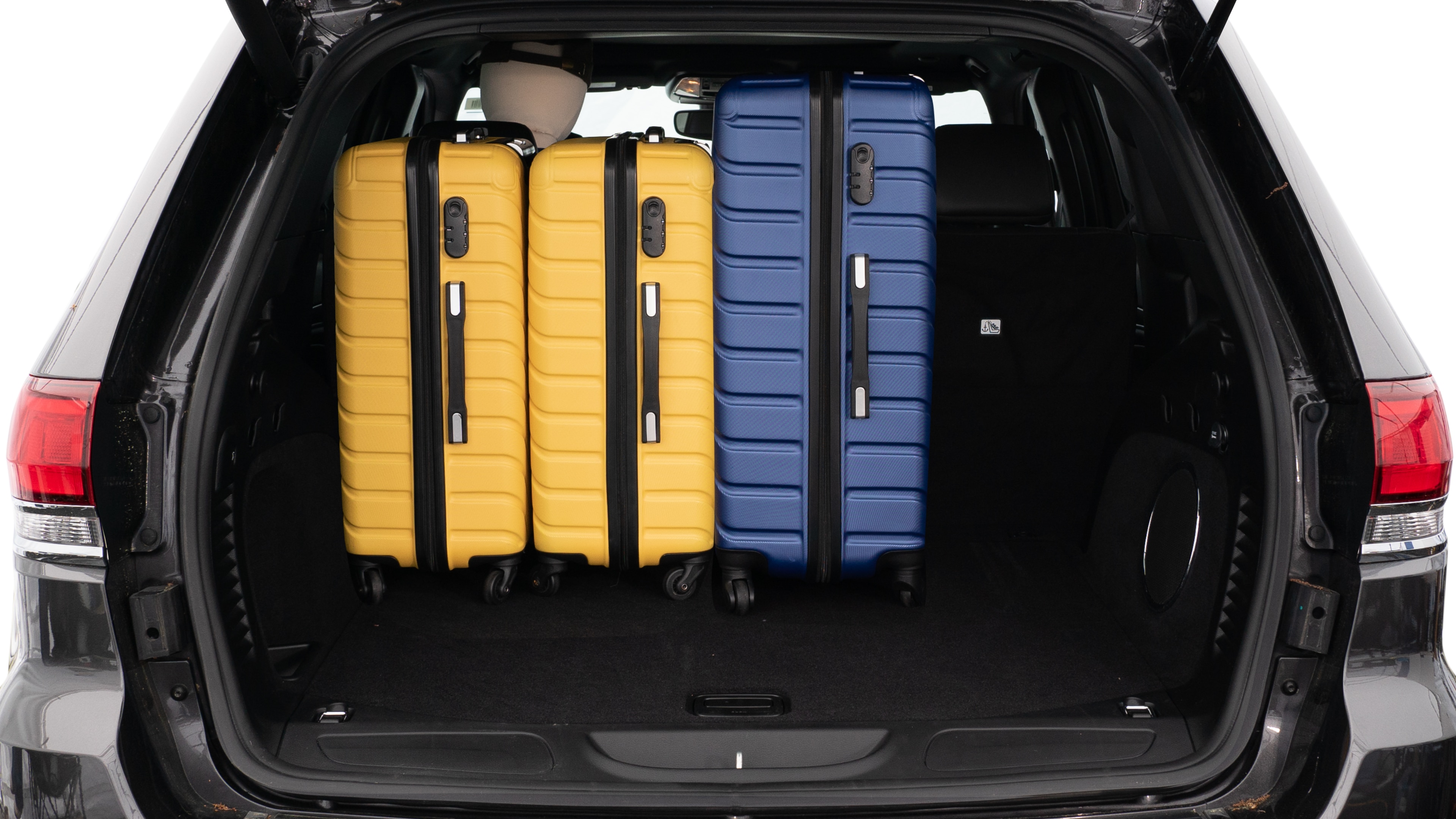 The trunk lid is open, showing a full view of the trunk space. Three large and two small suitcases are placed on there side