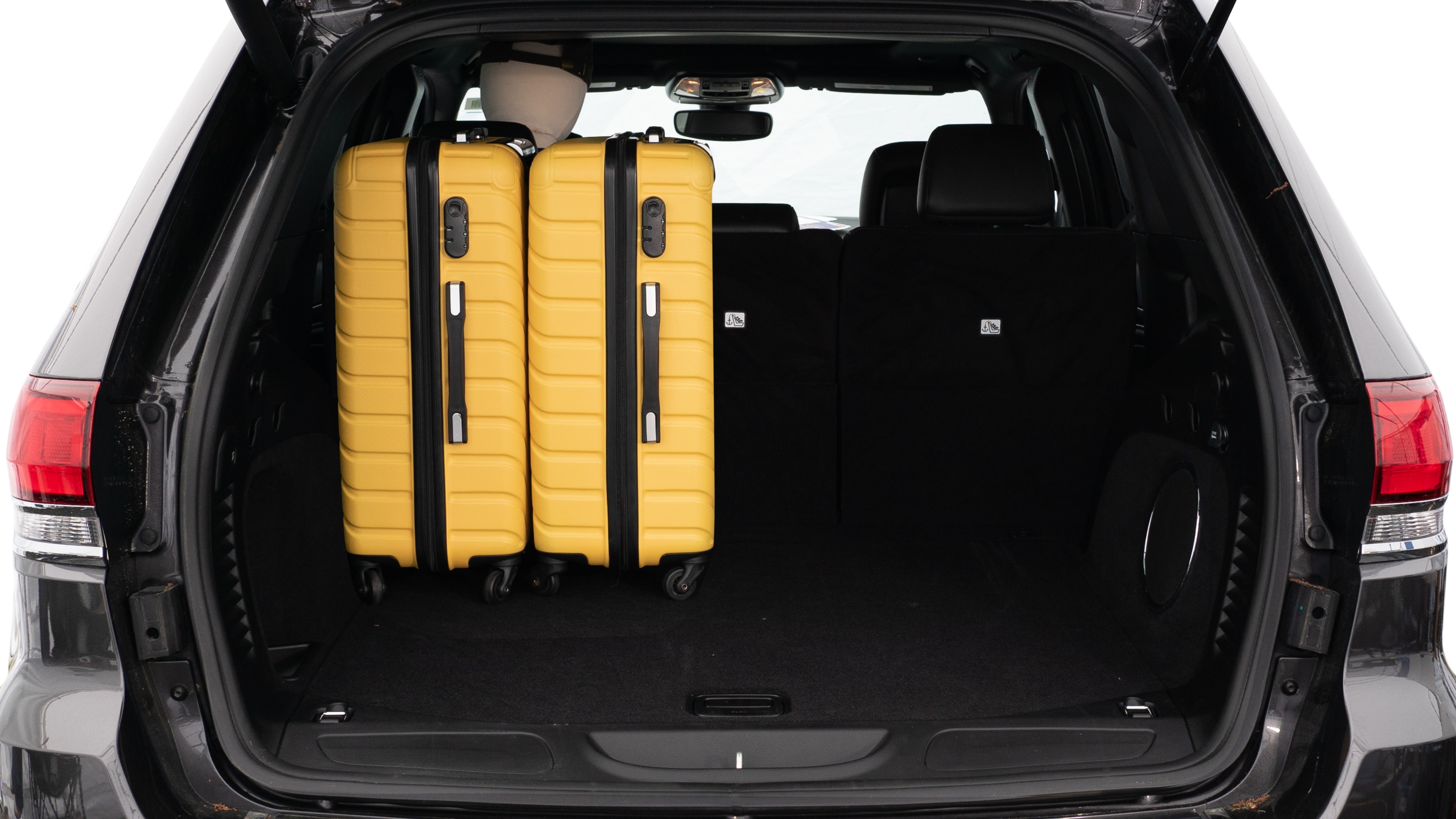 The trunk lid is open, showing a full view of the trunk space. Three large and two small suitcases are placed on there side