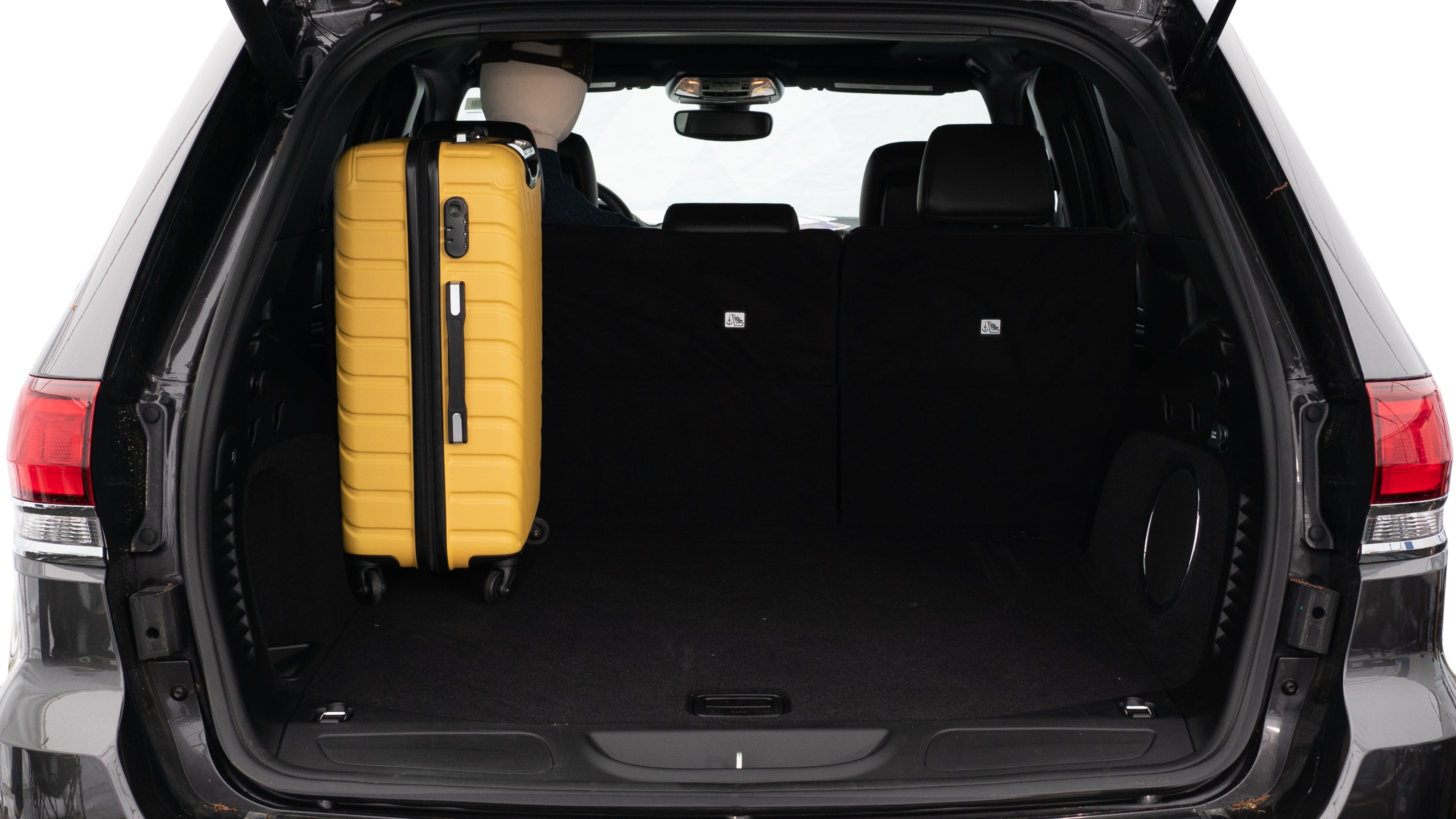 The trunk lid is open, showing a full view of the trunk space. Three large and two small suitcases are placed on there side